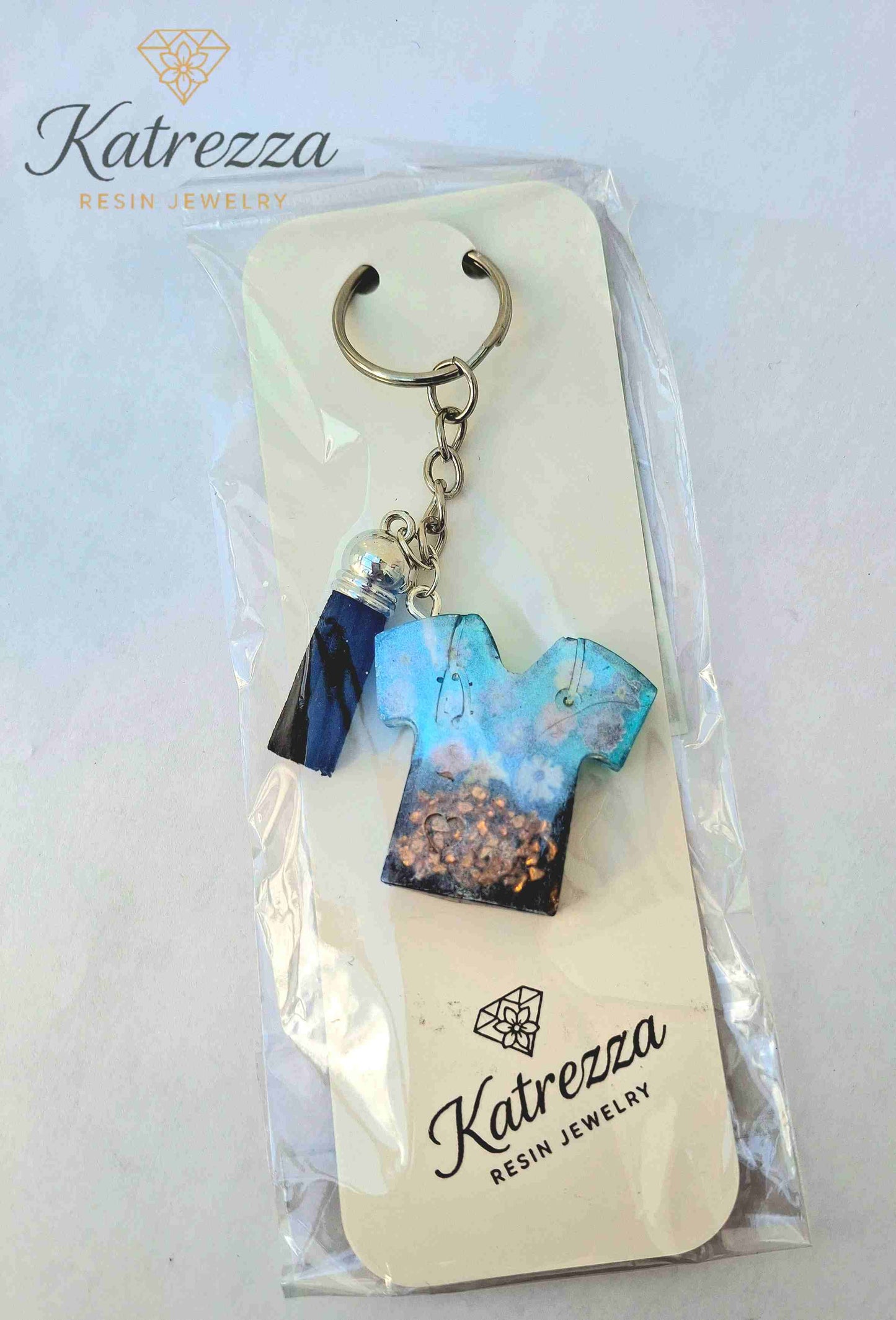 Packaged resin T-shirt keychain with tassel charm, ready for gifting.