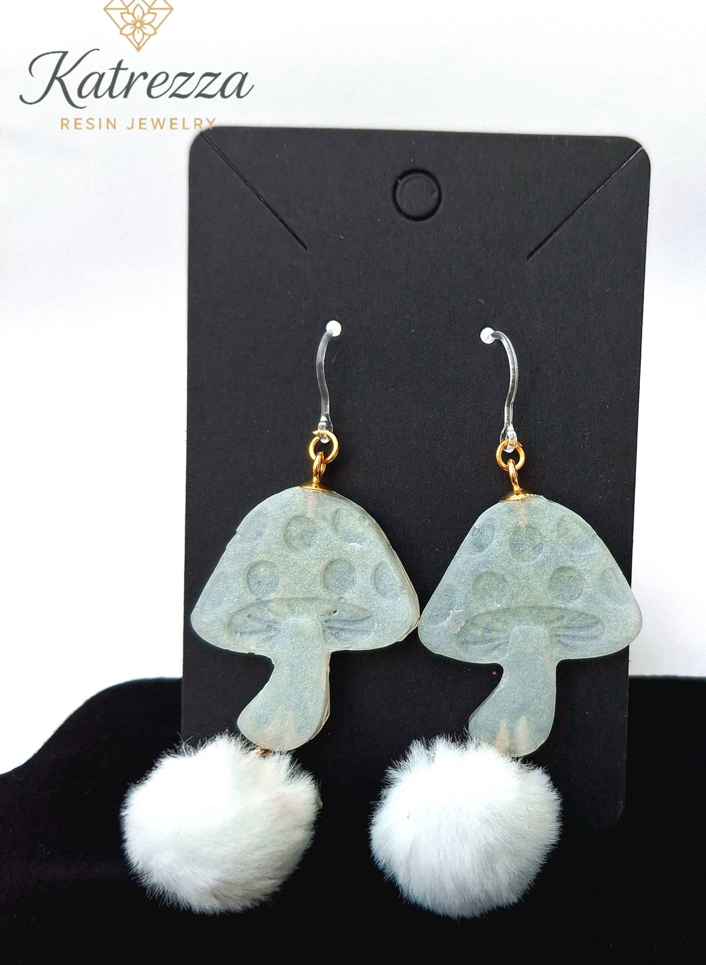 “Double-sided 8 cm mushroom-shaped resin earrings with shimmering white finish, fluffy white pom-poms, and hypoallergenic silicone hooks.”