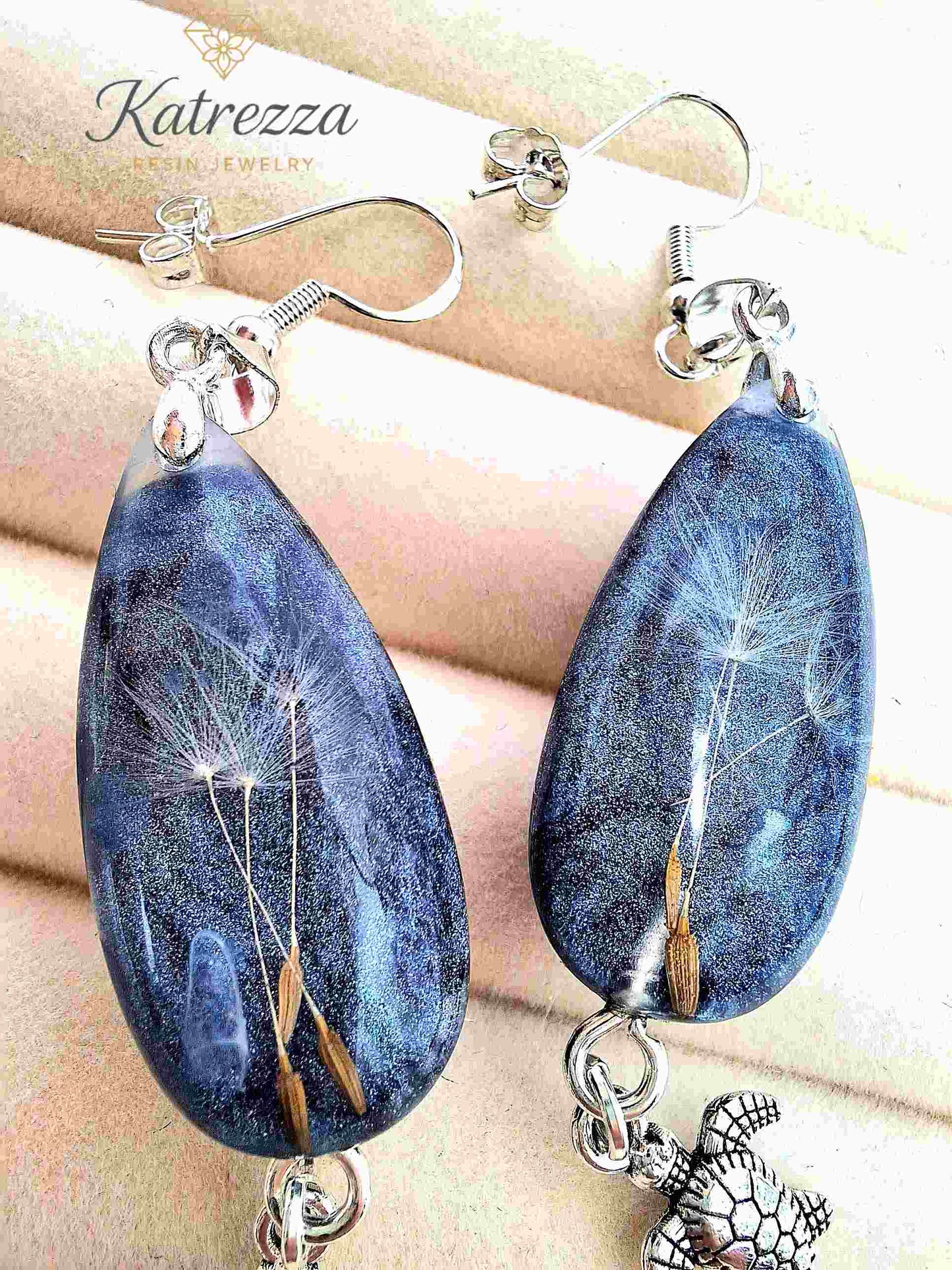 Teardrop resin earrings in grey-blue glitter with dandelion seeds and silver turtle charm.