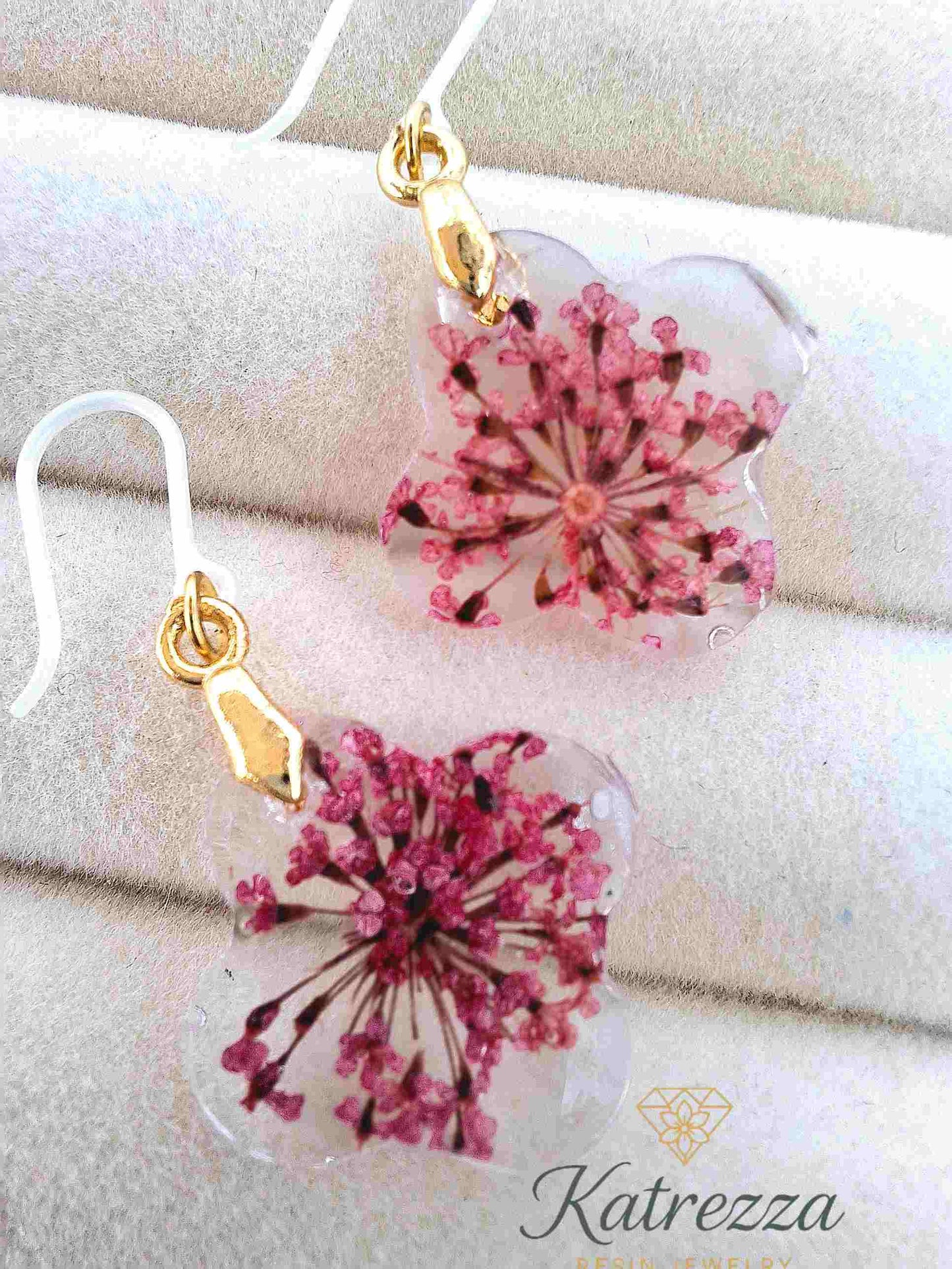 Clear resin earrings featuring real pink flowers and gold-tone accents