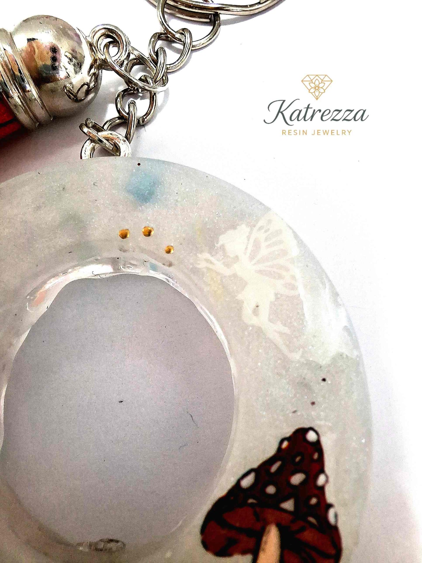 Close-up of resin O keychain showing red mushrooms and fairy silhouette.