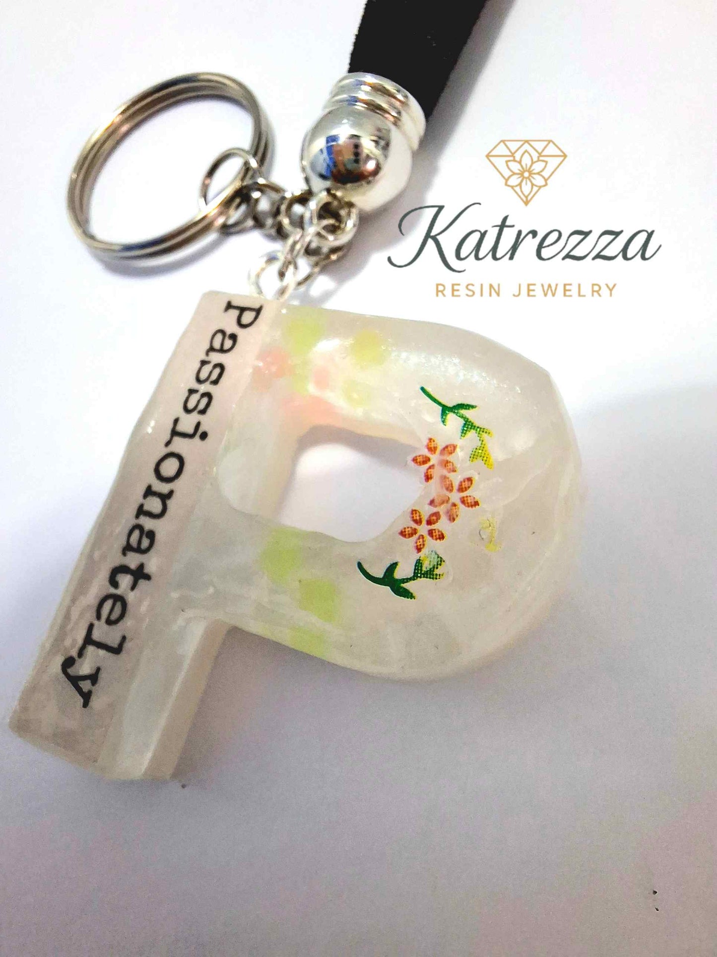 Close-up of resin P keychain with flowers and inspirational quote.