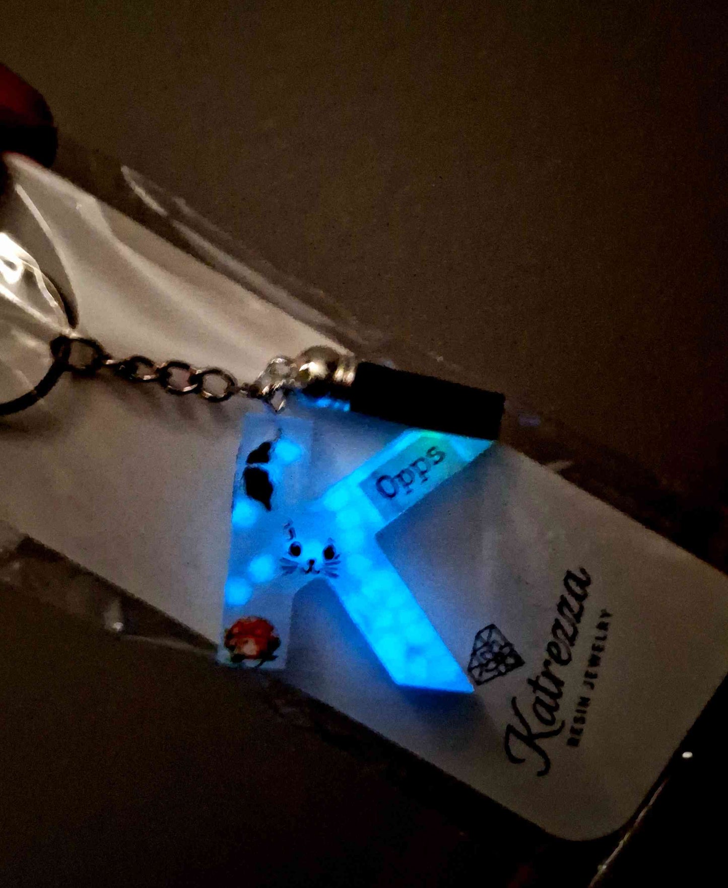 Glow-in-the-dark resin K keychain glowing blue in the dark.