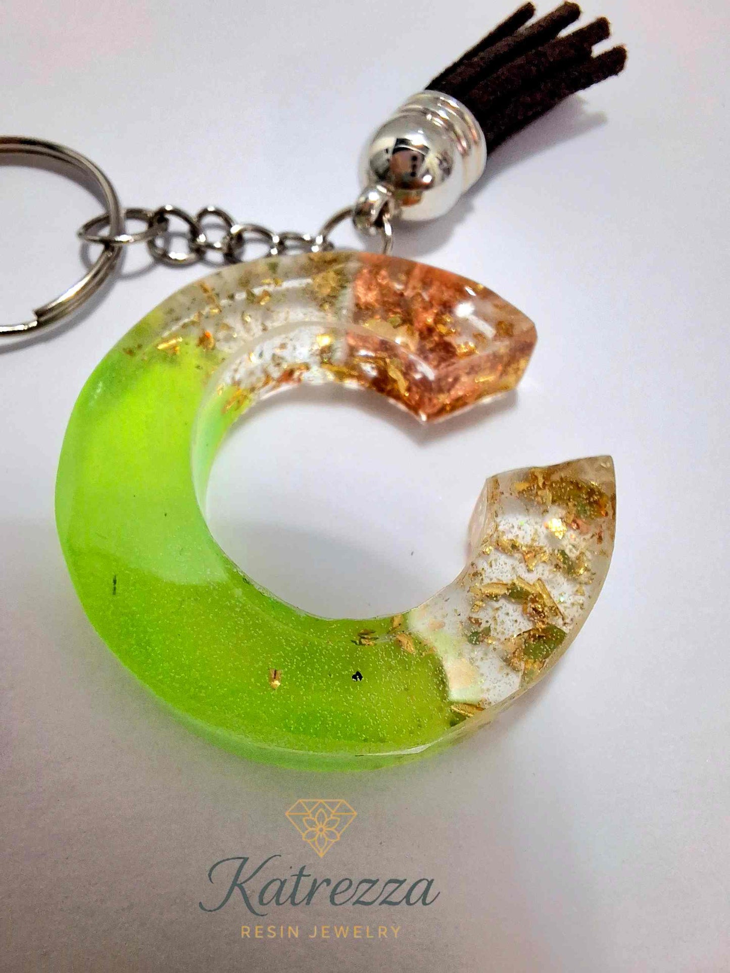 Handmade resin C keychain in gradient green with sparkling gold foil and metallic shimmer.