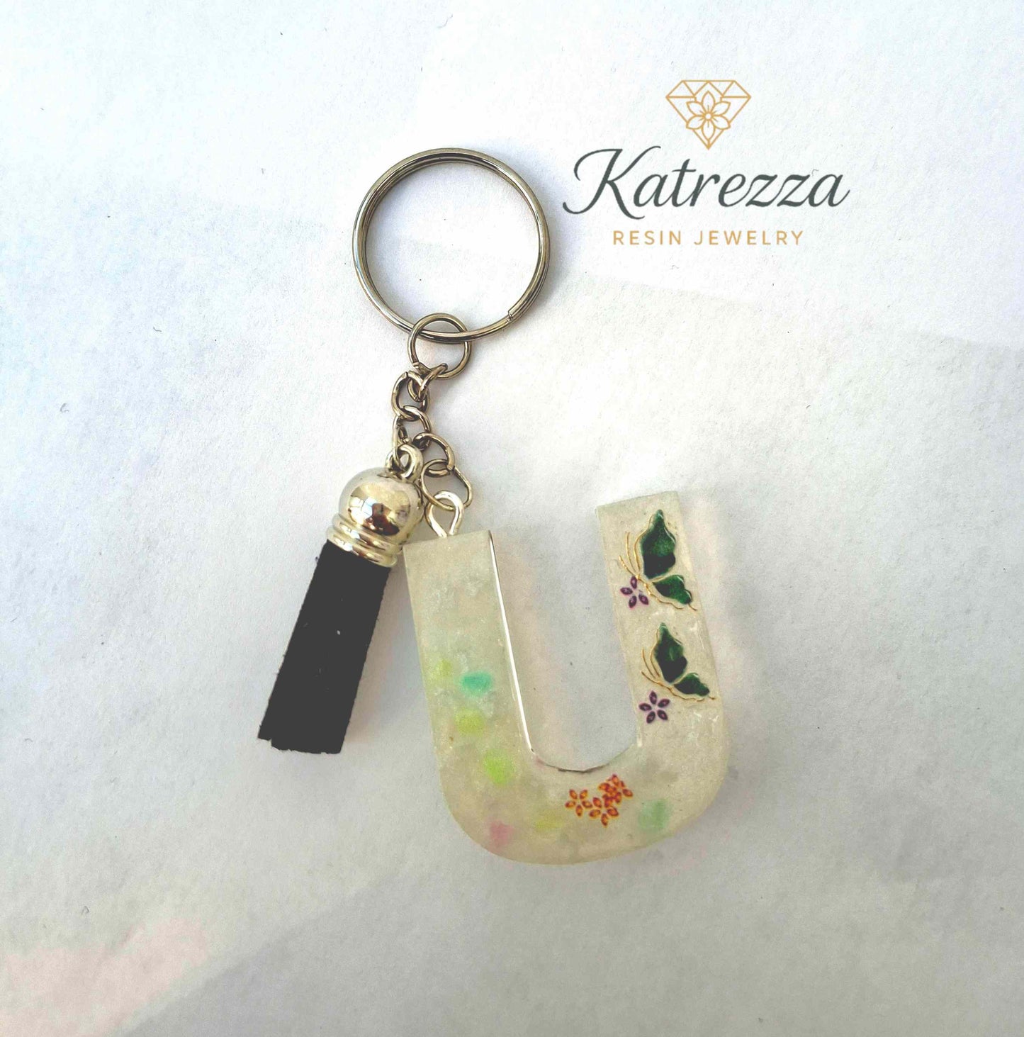 Close-up of resin letter U keychain showing butterflies and floral desi