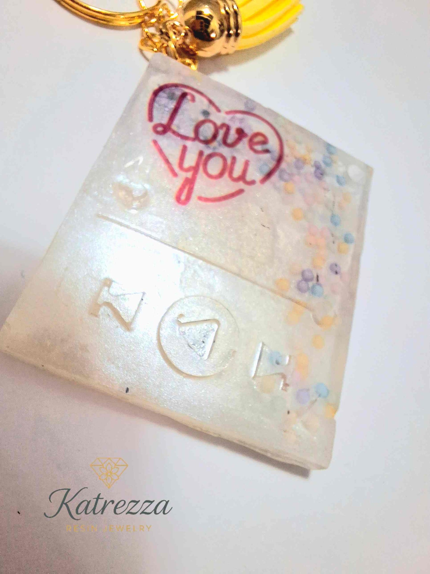 Double-sided handmade resin keychain showing both love messages with yellow tassel.