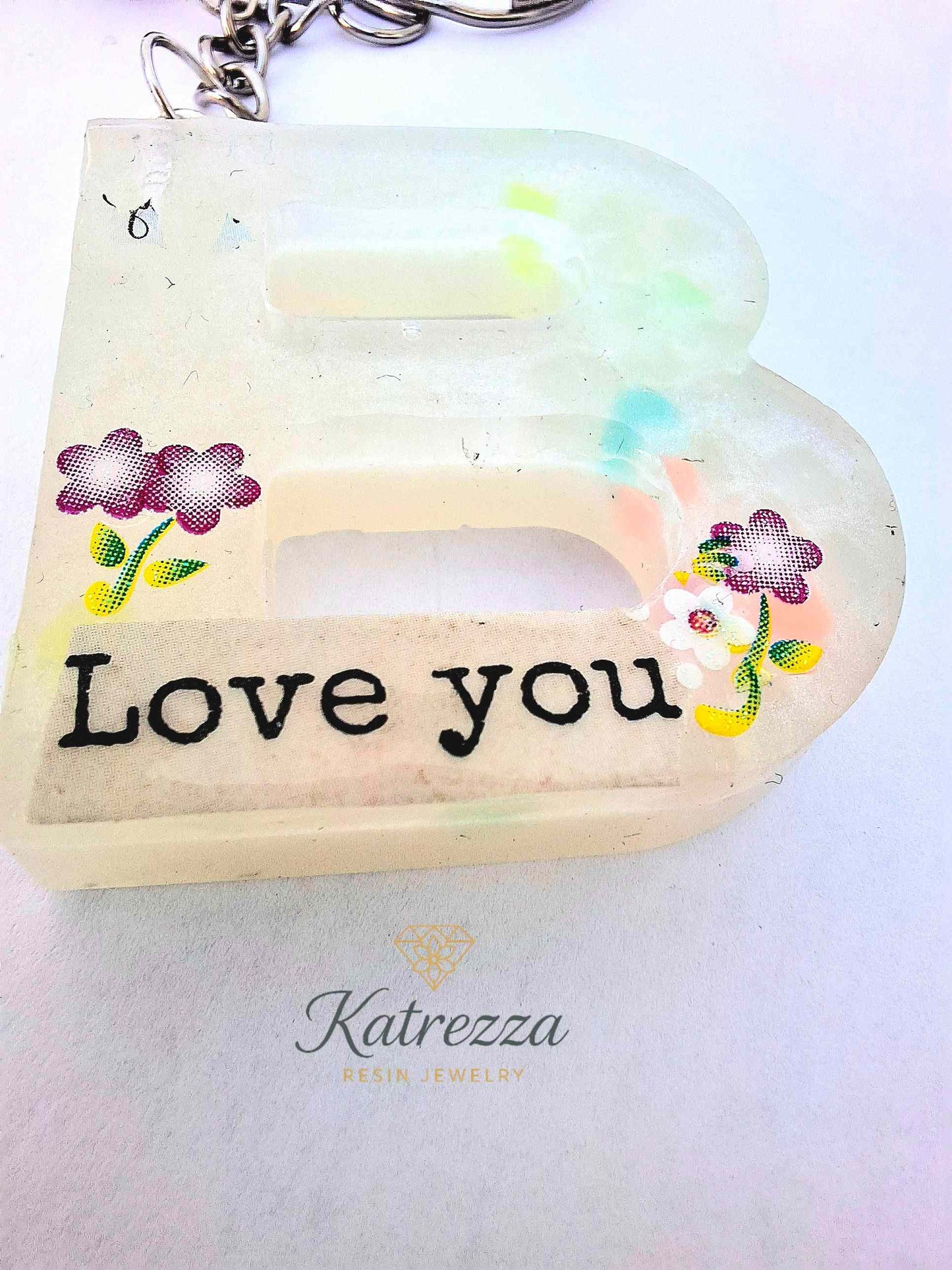 “Glow-in-the-dark resin B initial keychain shining in the dark with Love You message.