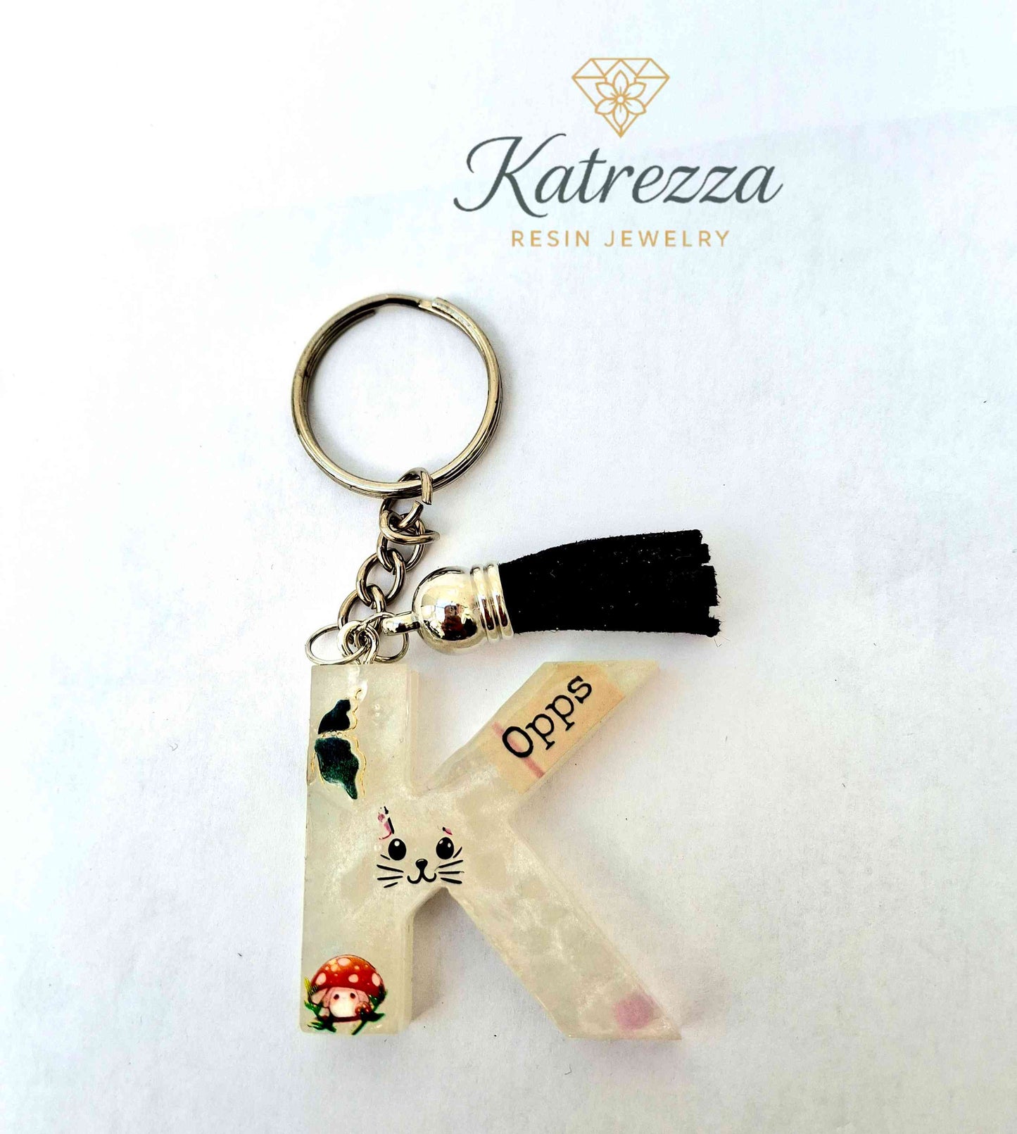 Resin letter K keychain with butterfly, cat face, mushroom stickers and tassel charm.