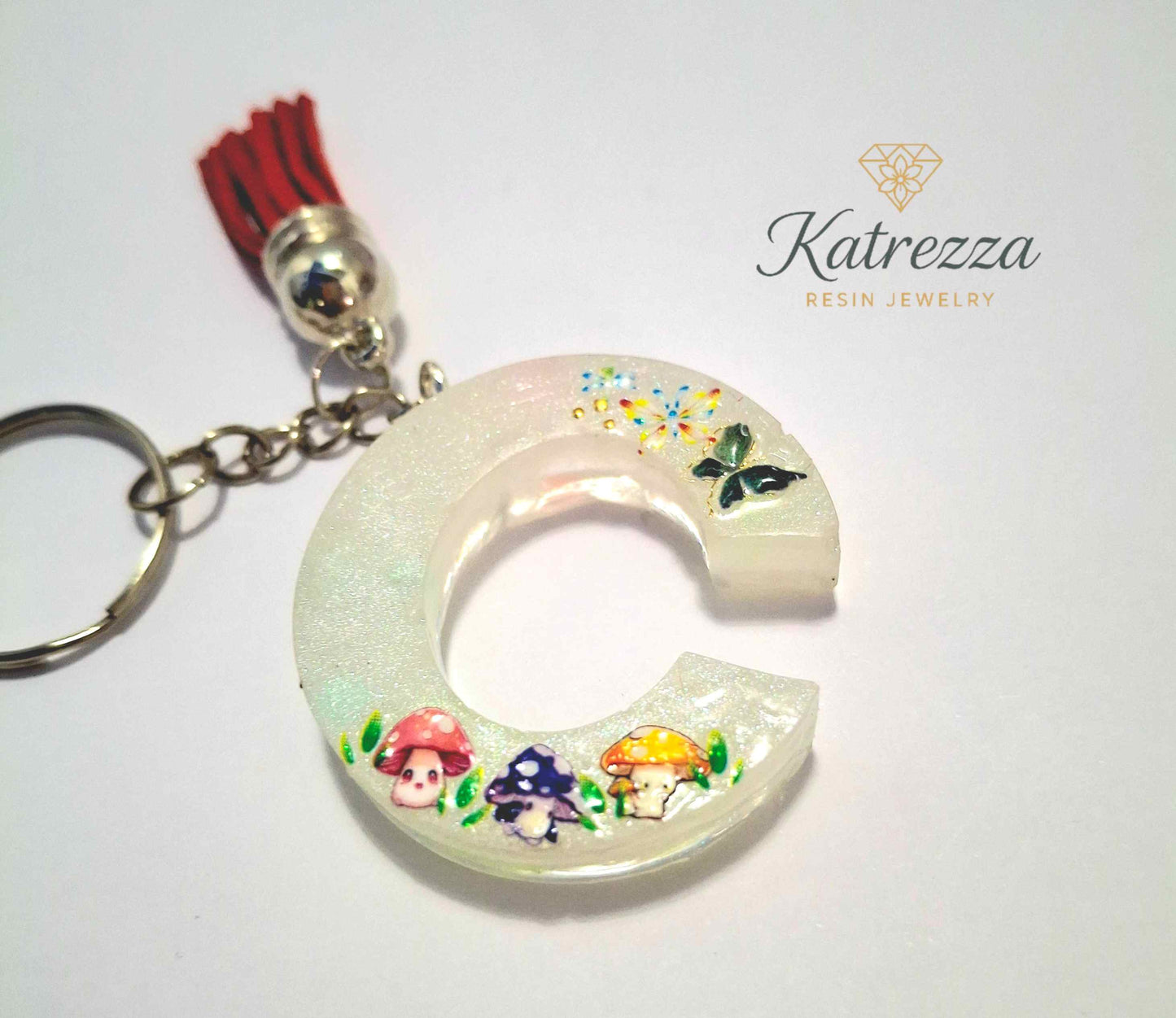 Close-up of resin letter C keychain featuring mushrooms and butterfly design.