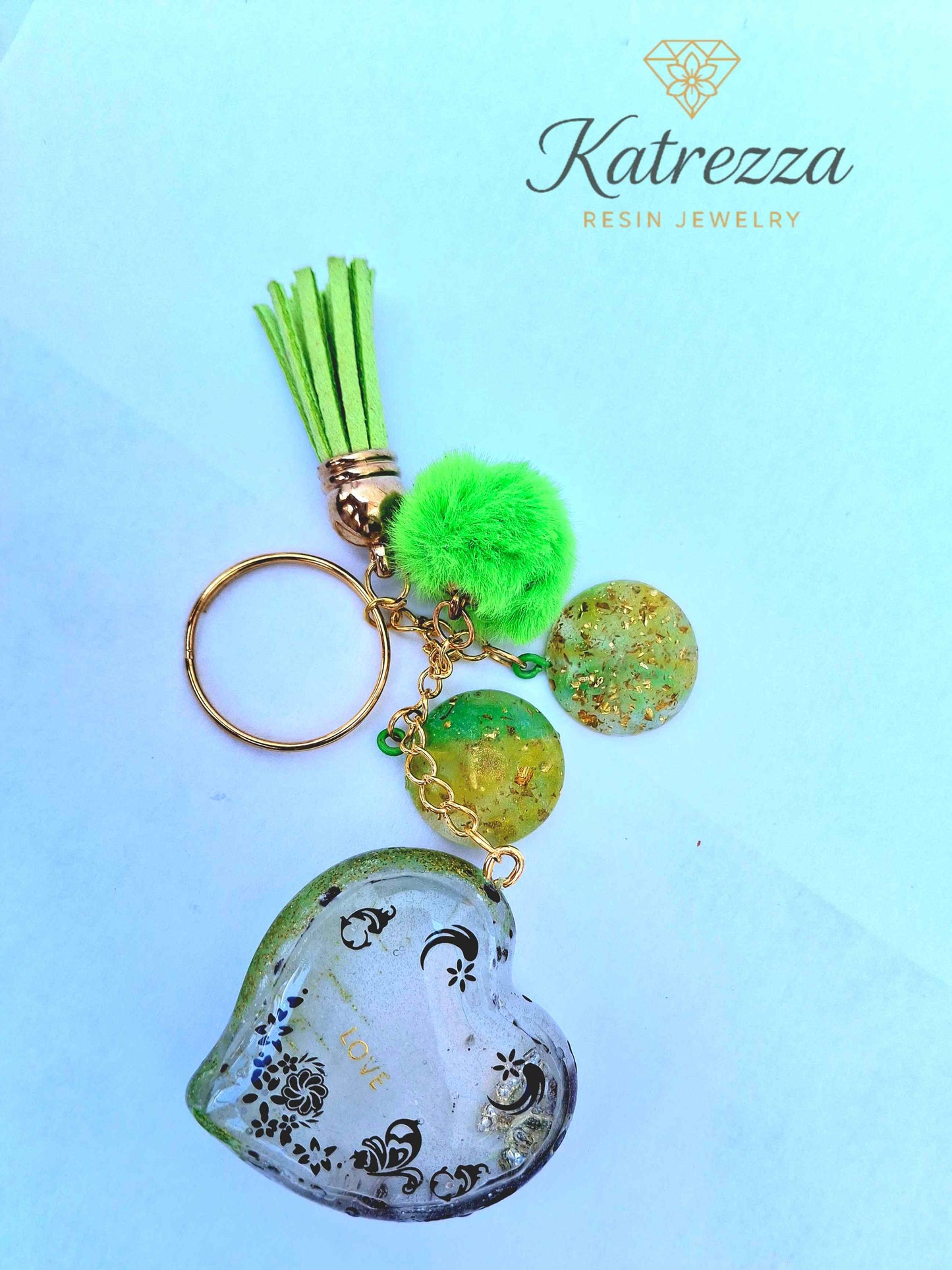 Green resin heart keychain with LOVE inscription, floral design, tassel, and pom charm – Katrezza Handmade Accessories"