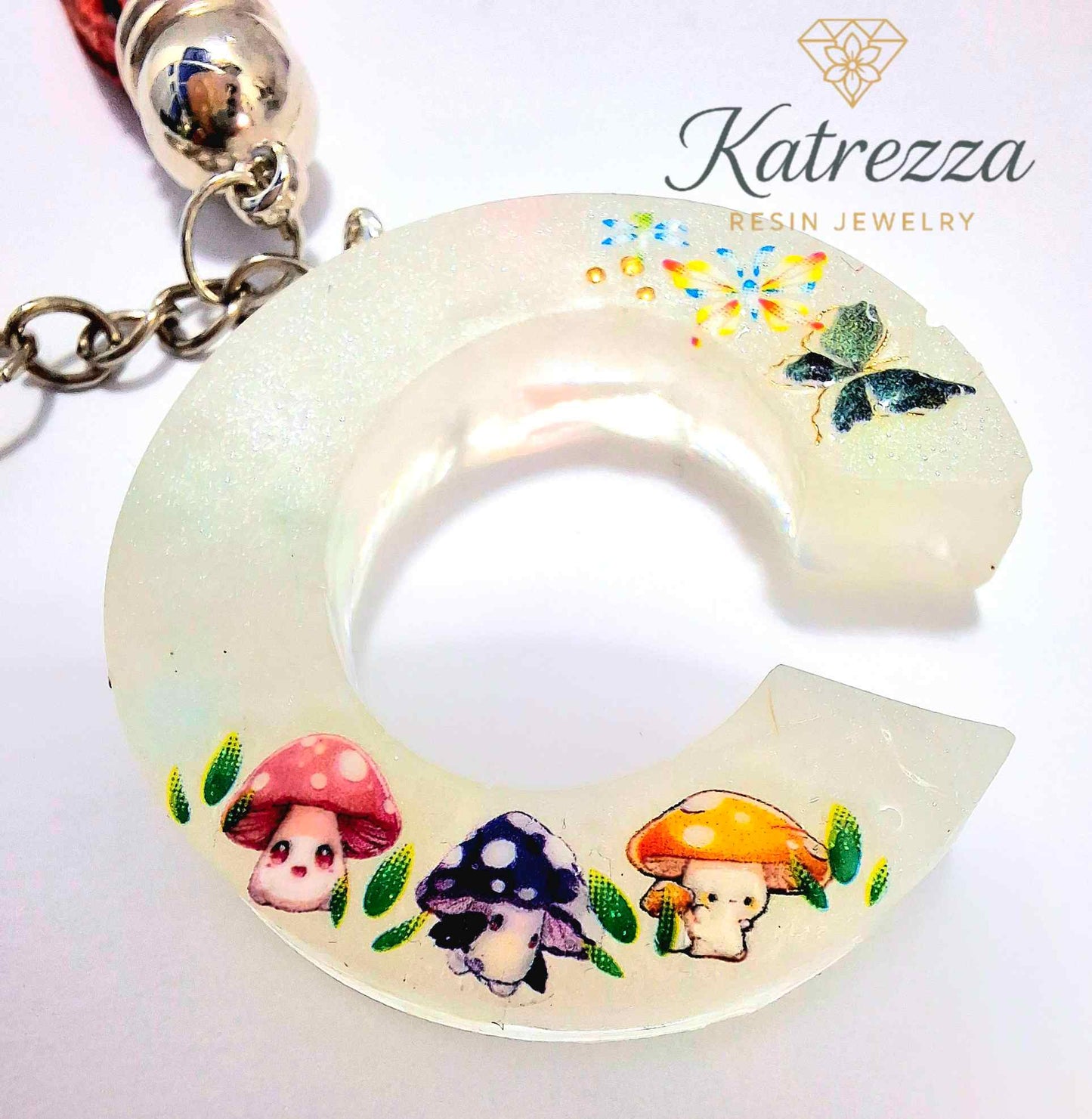 Resin letter C keychain with mushroom stickers and butterfly details in night glow.