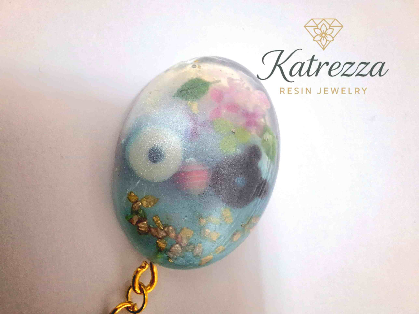 Oval resin keychain with donuts, lollipop, florals, and gold flakes, finished with blue tassel and gold keyring – Katrezza