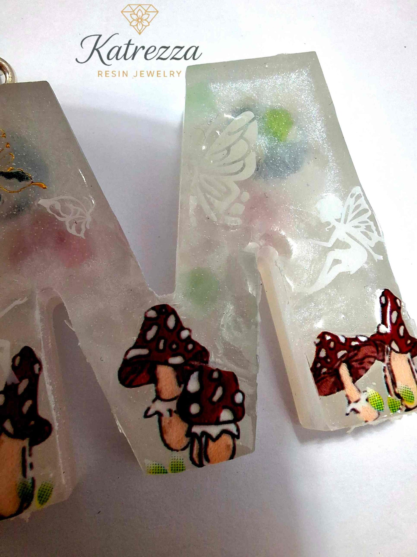 Glow-in-the-dark resin M keychain with fairy and mushroom designs.