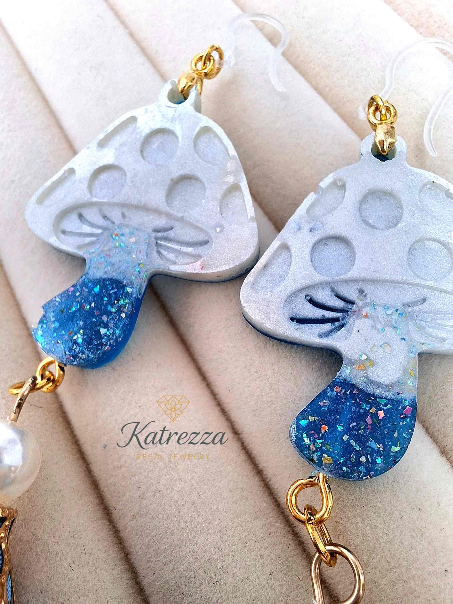 "Pair of double-sided resin mushroom earrings with pearl beads and blue flower charms displayed on black card – Katrezza Jewelry"