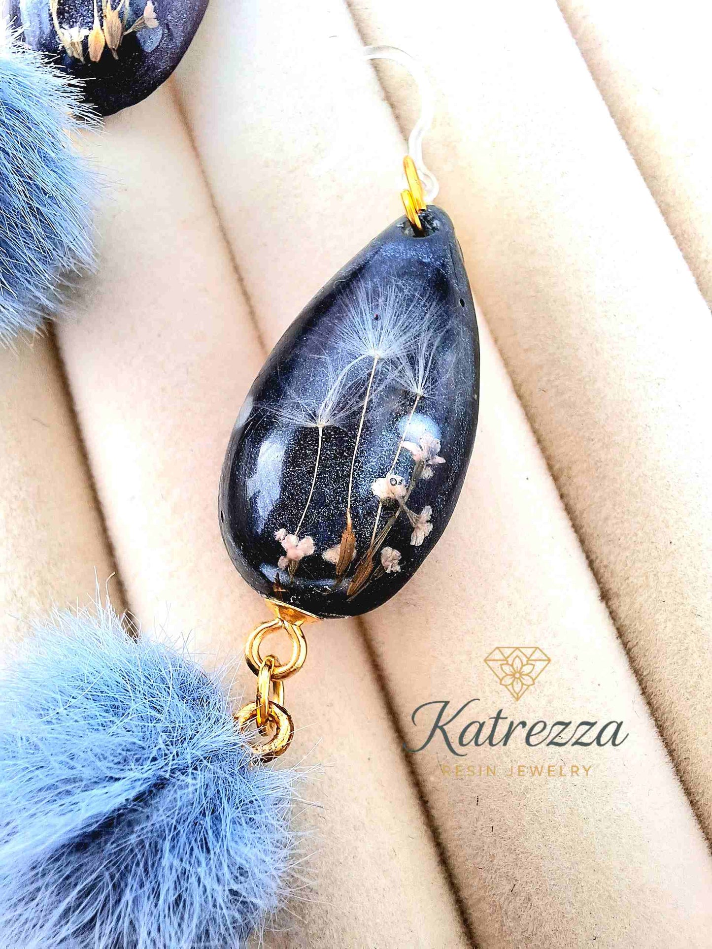 "Pair of 7.5cm resin earrings with glittery grey-black teardrops, preserved flowers, dandelion seeds, and fluffy blue pom-poms – Katrezza Jewelry"