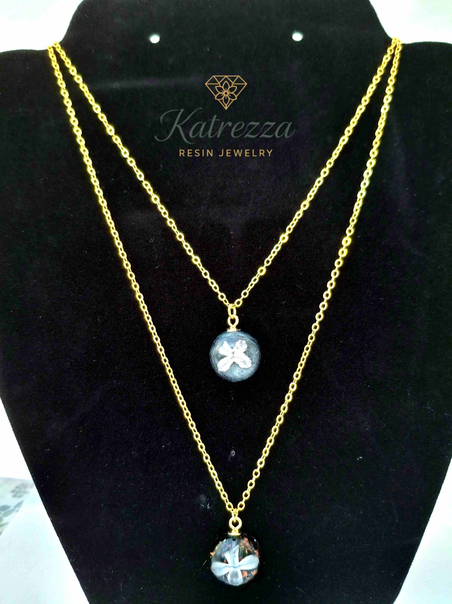 Double pendant resin necklace with real lilac flowers preserved in resin, glitter accents, on a gold double chain – handmade Katrezza jewelry.