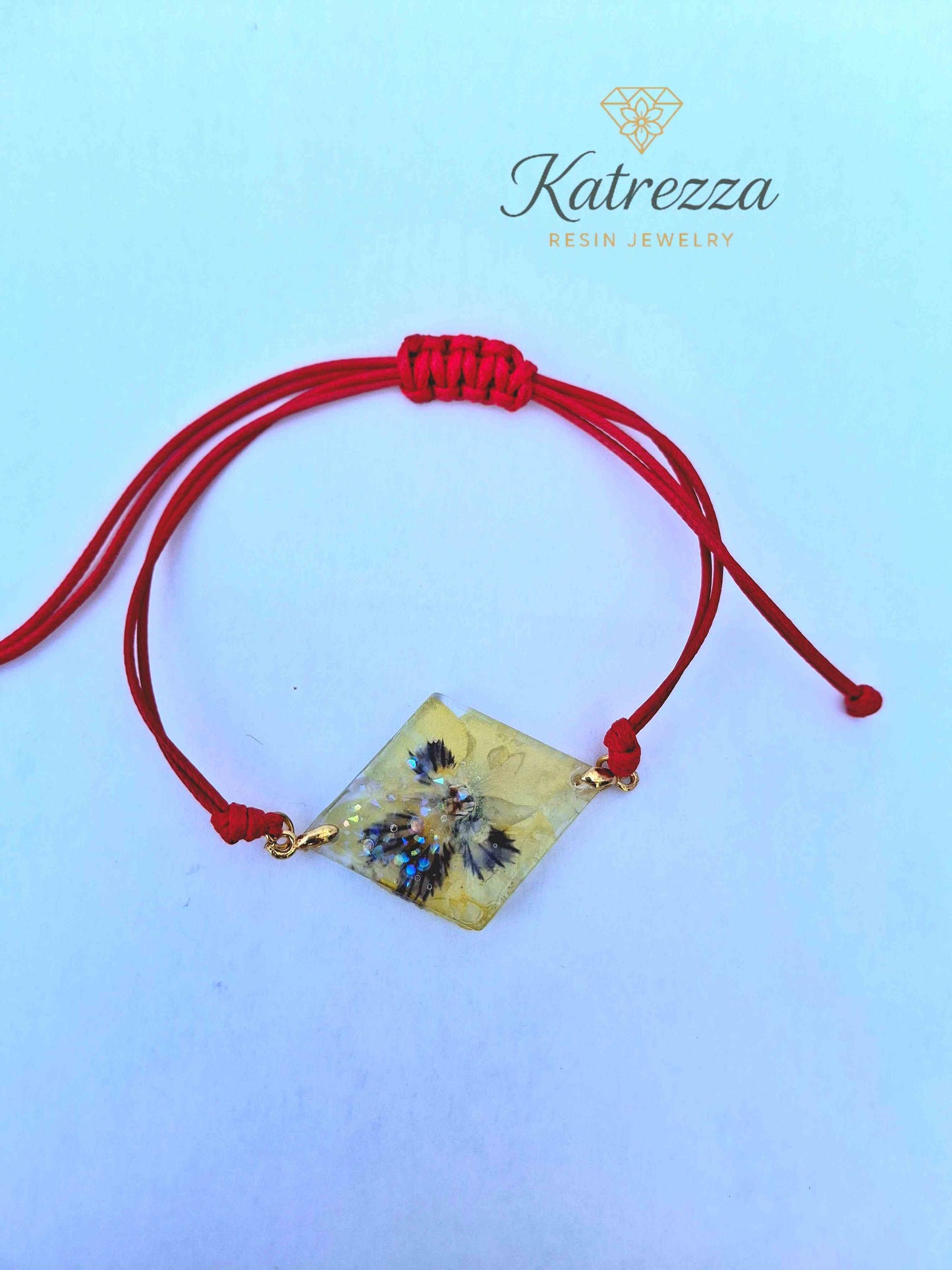 Close-up of clear resin bracelet charm with preserved pansy and sparkles.