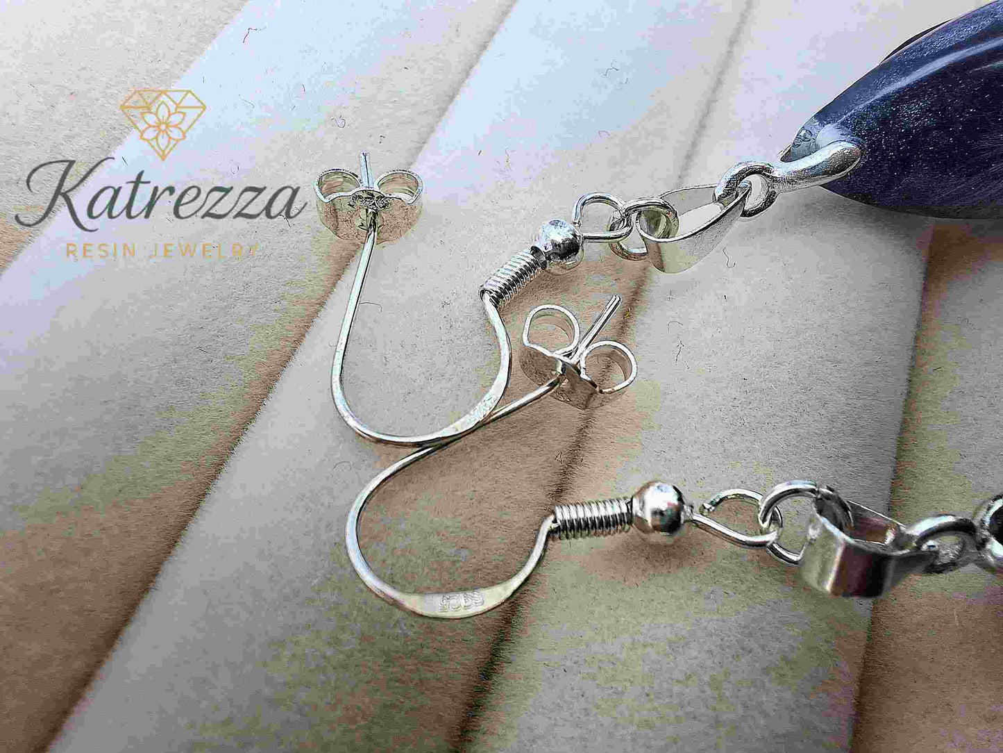 Side view of resin teardrop earrings with dandelion seeds and silver turtle charm.