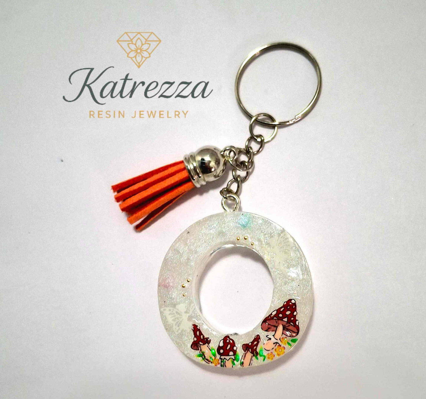 Resin letter O keychain with mushroom design and orange tassel.