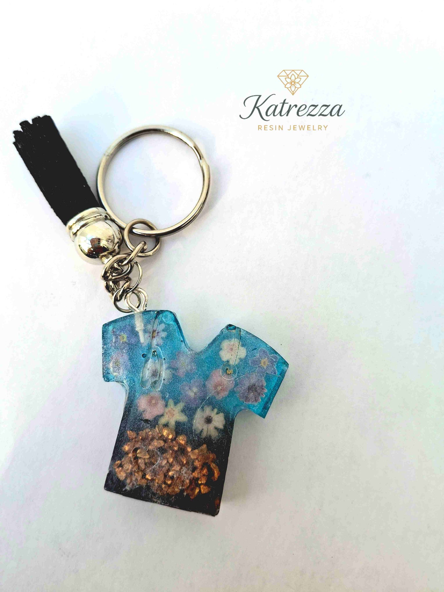 Handmade resin T-shirt keychain decorated with colorful flower stickers.
