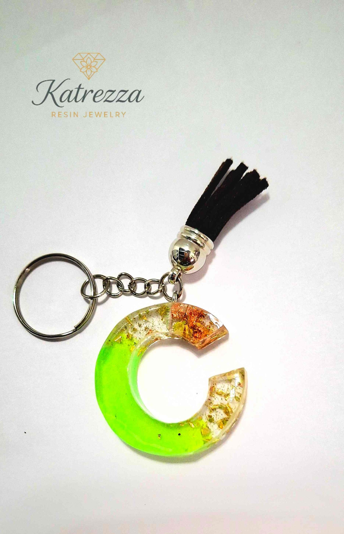 Side angle of green resin letter C showing translucent resin with embedded foil pieces.