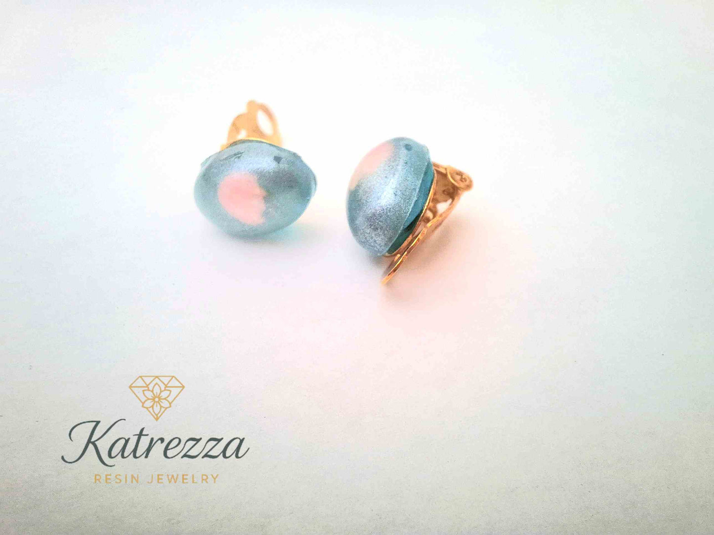 “Handmade kids resin clip-on earrings with shimmering blue dome and pink detail – Katrezza jewellery.”