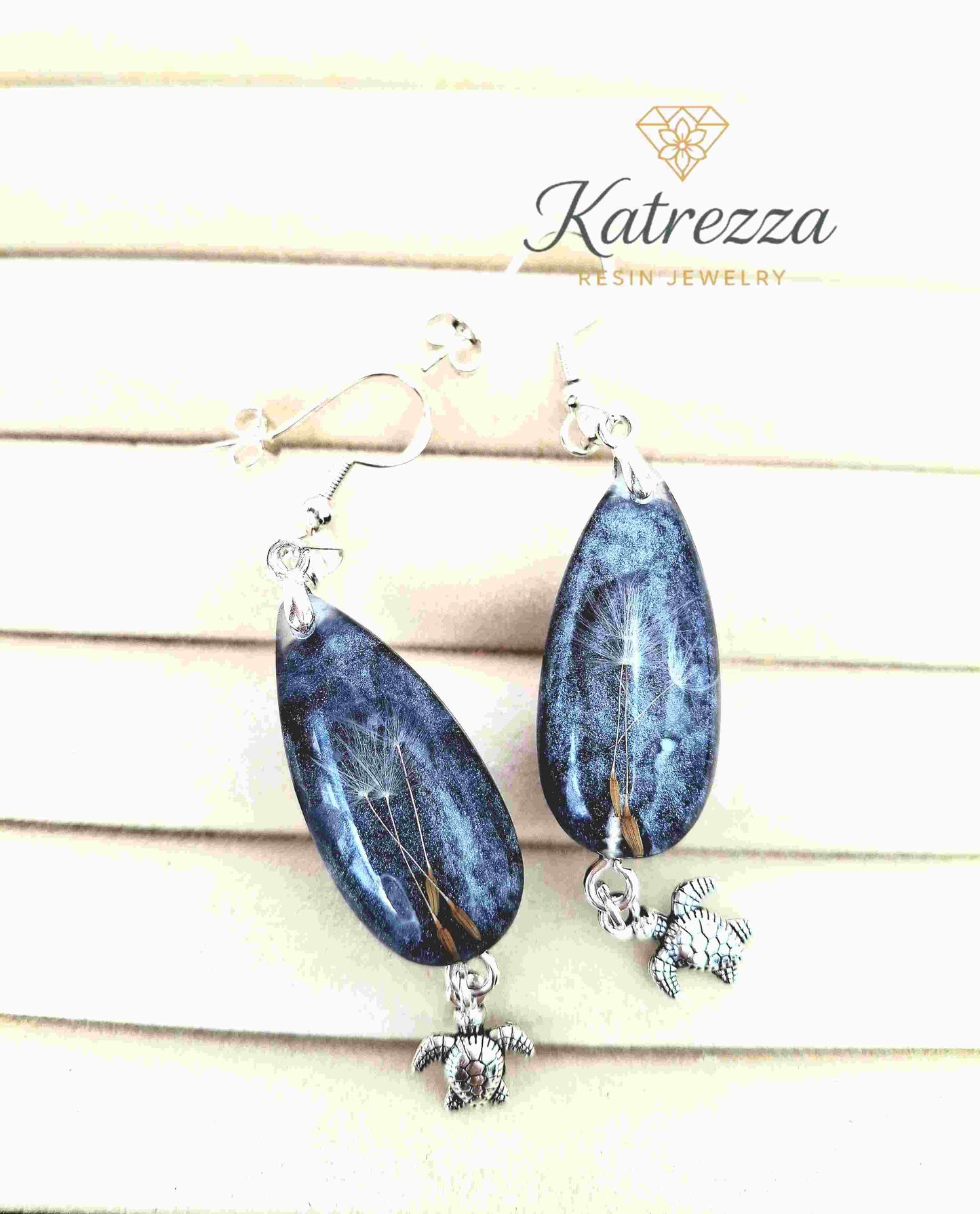 Teardrop resin earrings in grey-blue glitter with dandelion seeds and silver turtle charm.