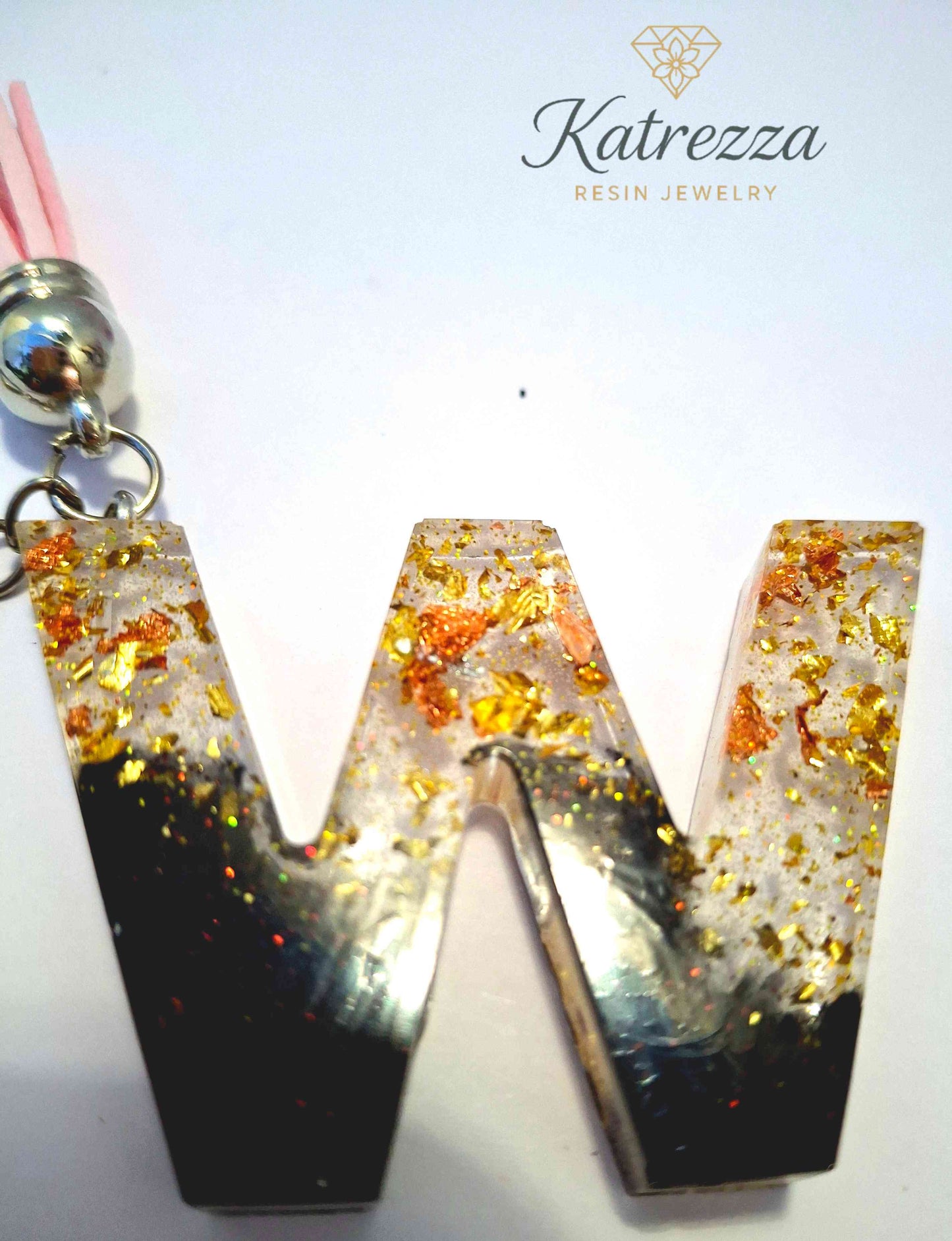 Close-up of resin W keychain with gold and copper foil flakes.