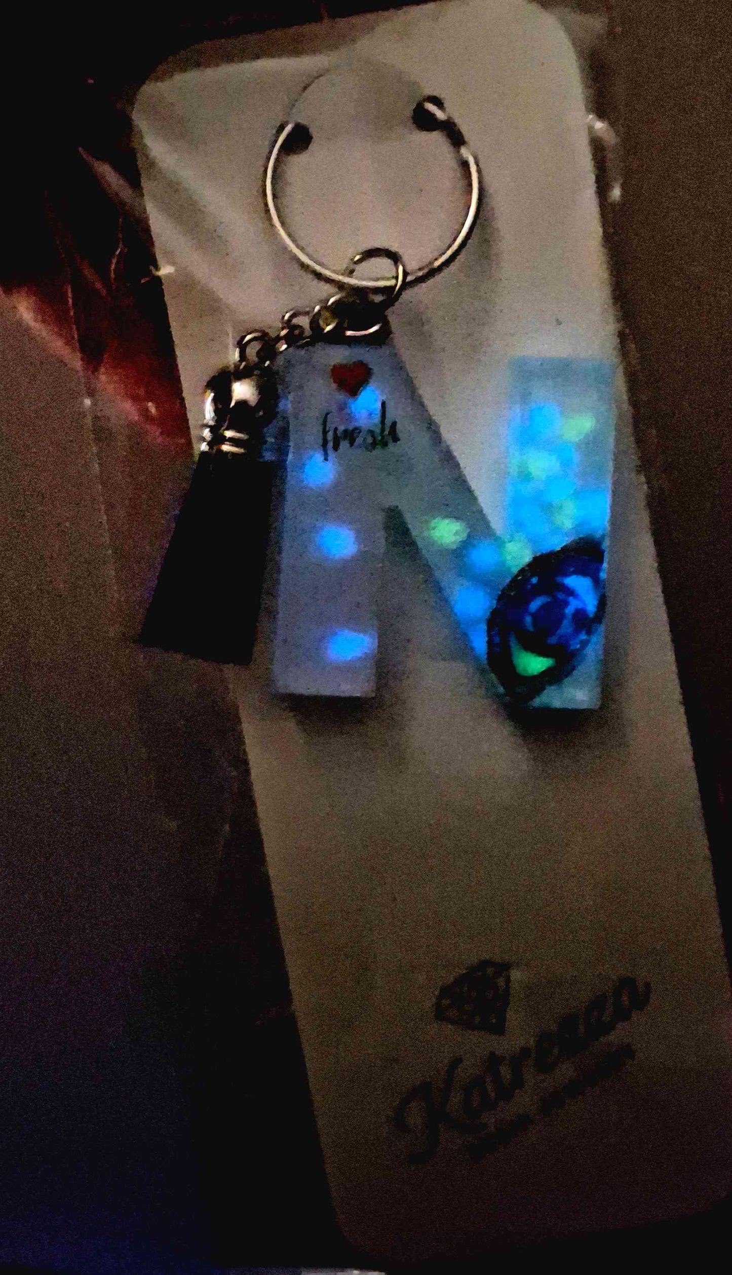 Close-up of resin N keychain showing eye artwork and inspirational quote.