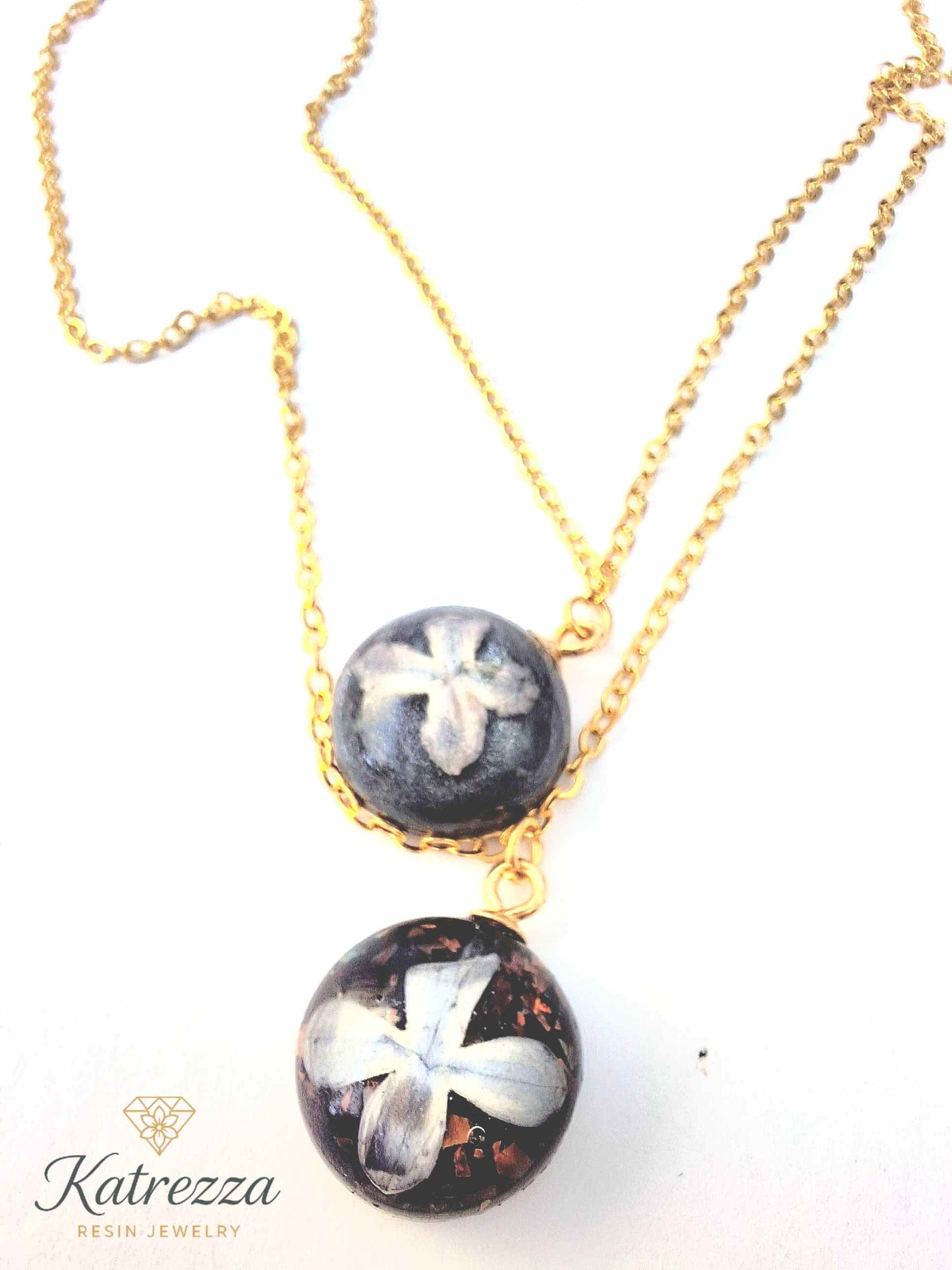 Double layer necklace with two resin pendants featuring real lilac flowers and glitter, on a gold chain – Katrezza artisan jewelry.