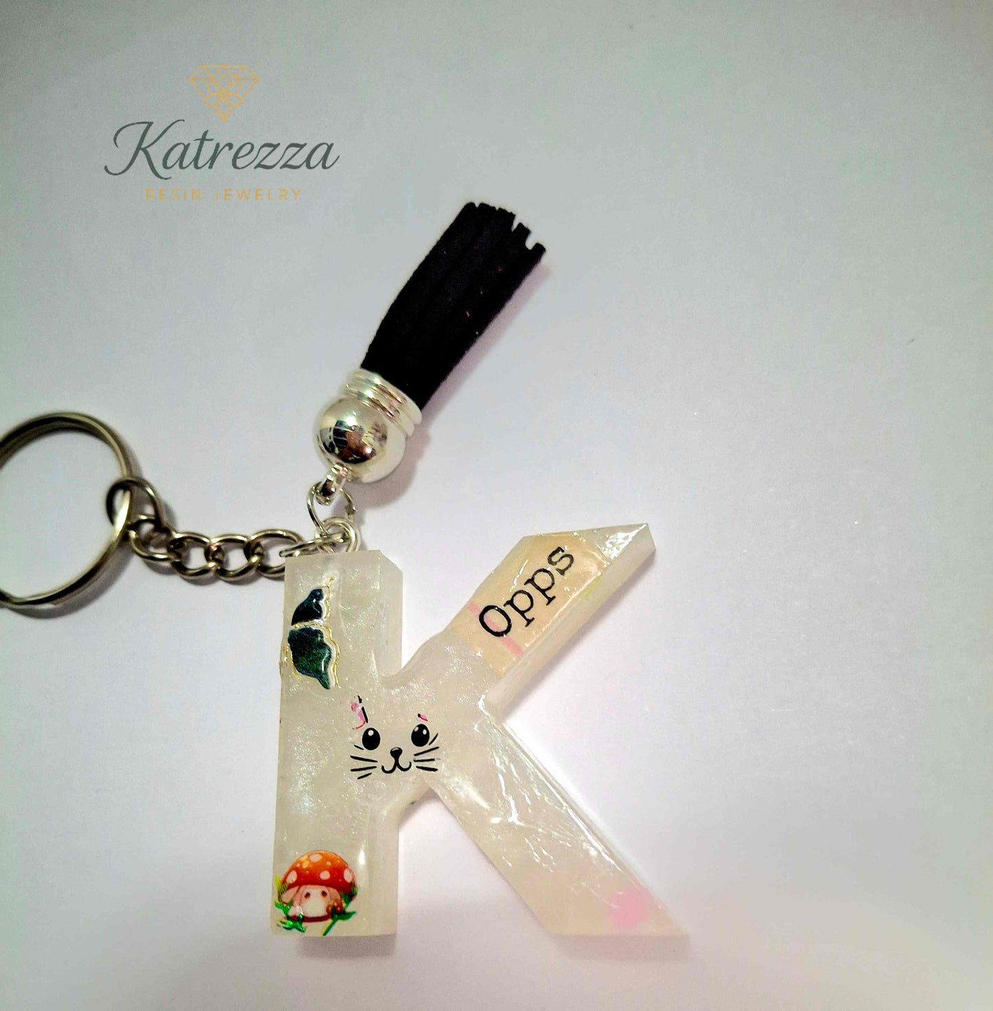 Resin letter K keychain decorated with mushroom, butterfly, and cat stickers.