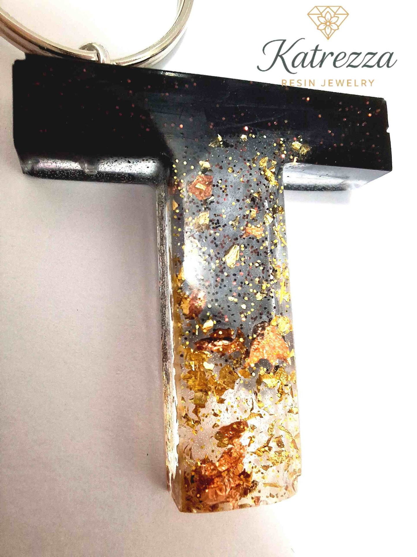 Close-up of resin letter T keychain featuring black resin blending into gold and copper flakes, Katrezza Resin Jewelry.