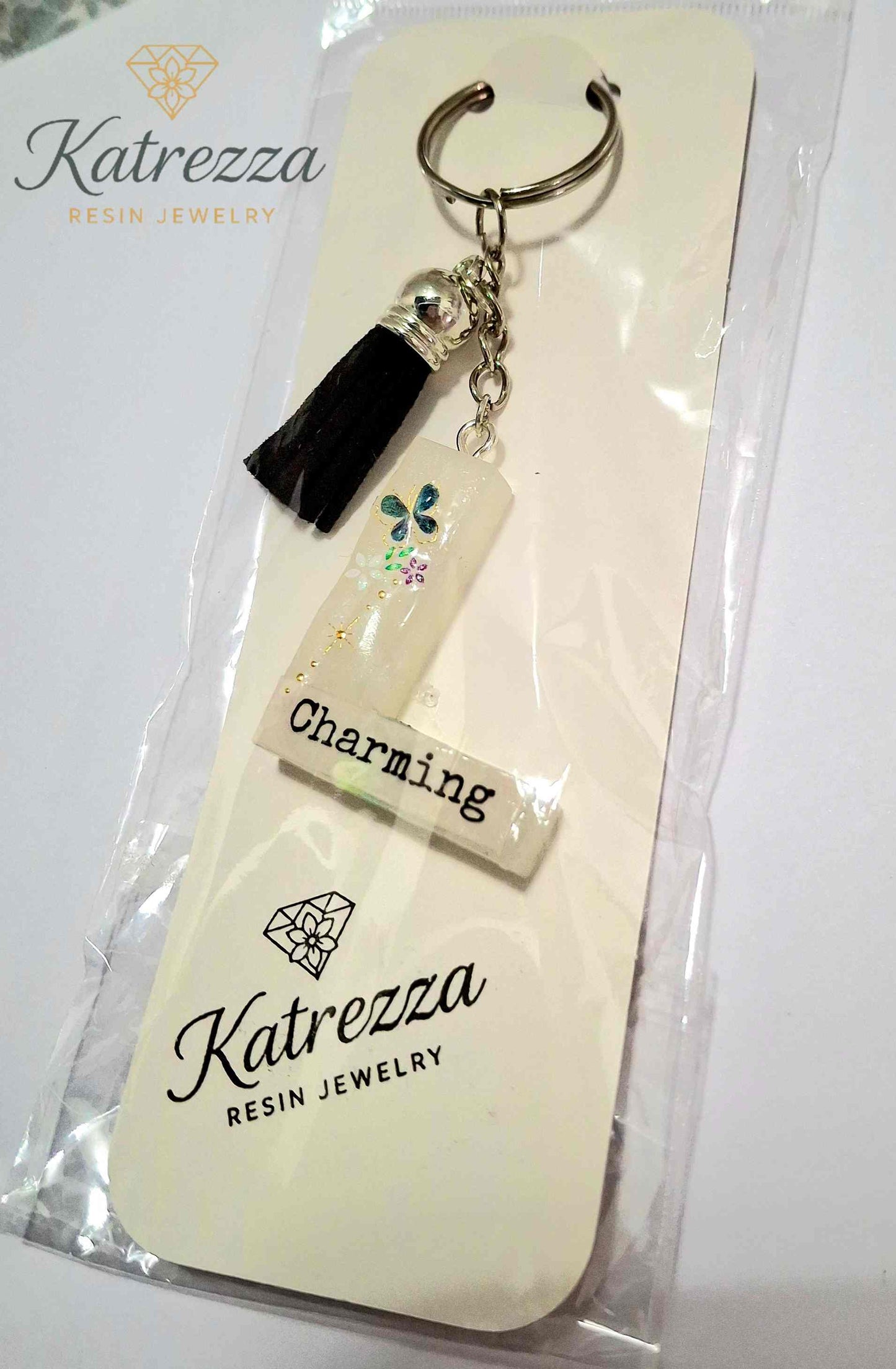 Handmade resin L keychain with butterfly and floral details.