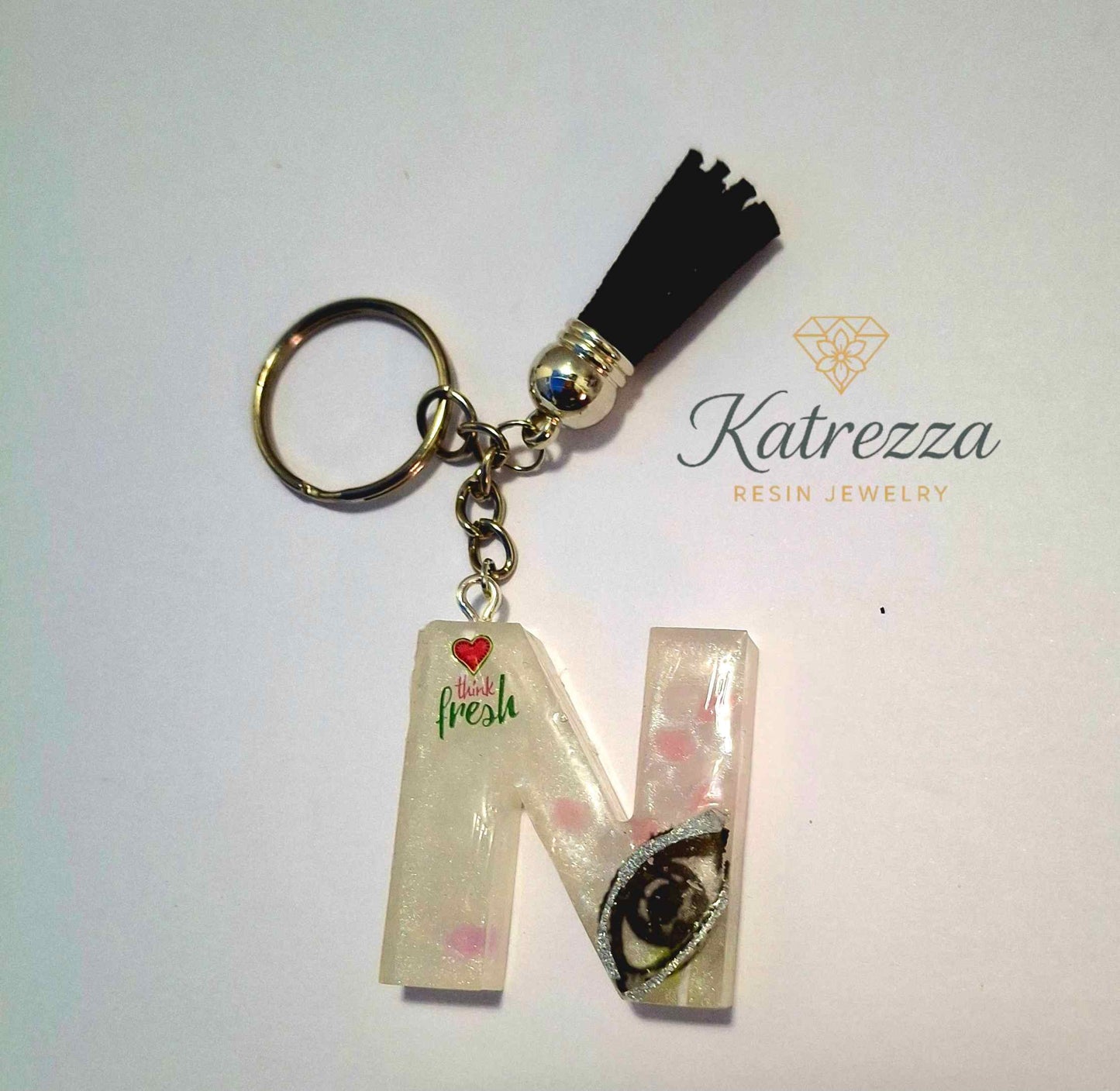 Resin letter N keychain with “Think Fresh” quote and artistic eye design.