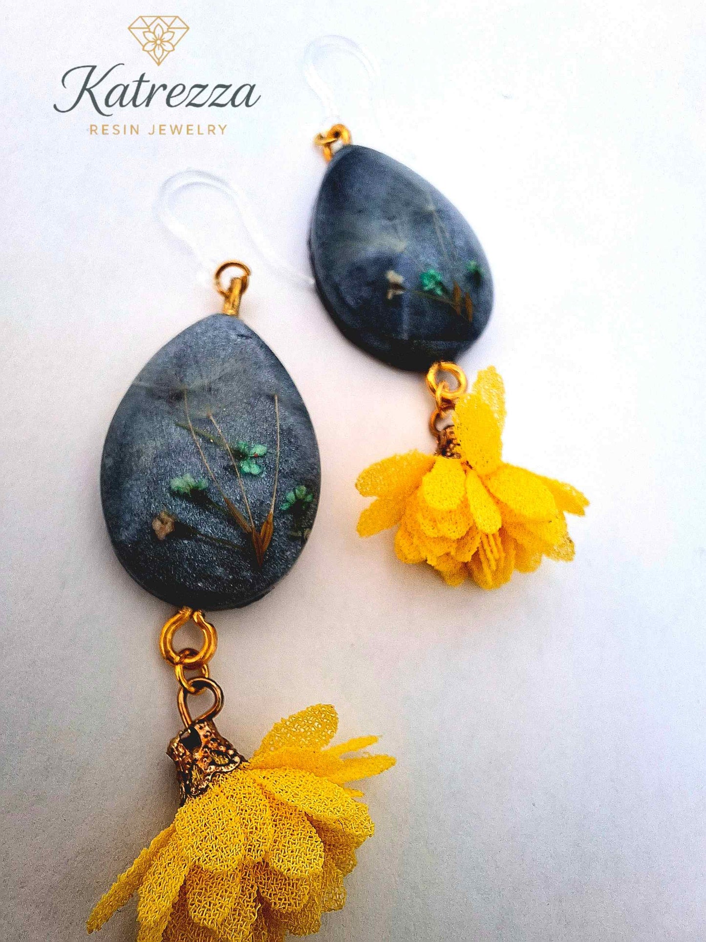 “Teardrop resin earring with preserved flowers and dandelion seed in dark resin, gold details, hypoallergenic silicone hook, and yellow tassel – 7 cm