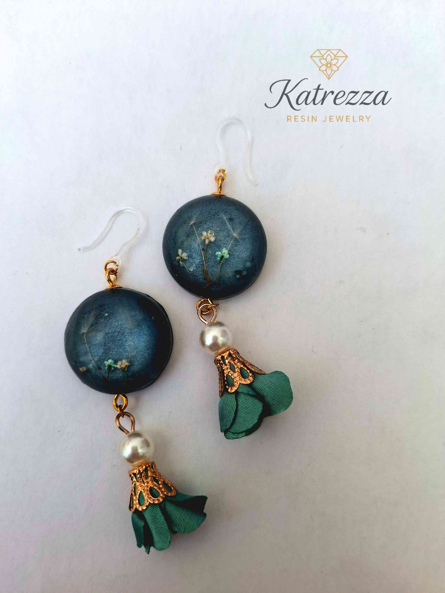 “Close-up of handmade 8 cm resin earring with real pressed flowers, pearl bead, green tassel, and hypoallergenic hook – Katrezza jewelry.”