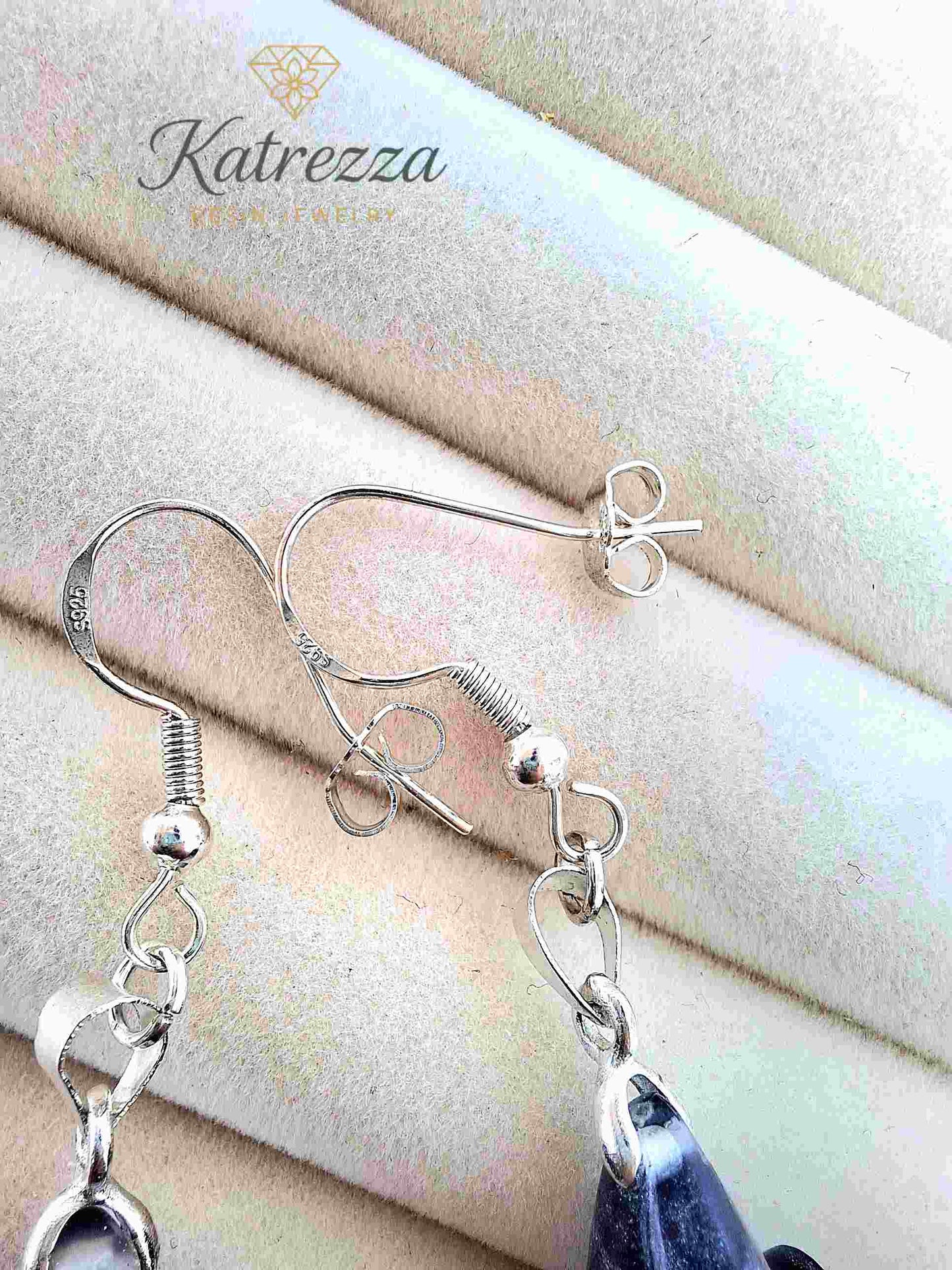 Close-up of glittery resin earrings with dandelion bouquet and sterling silver hooks.