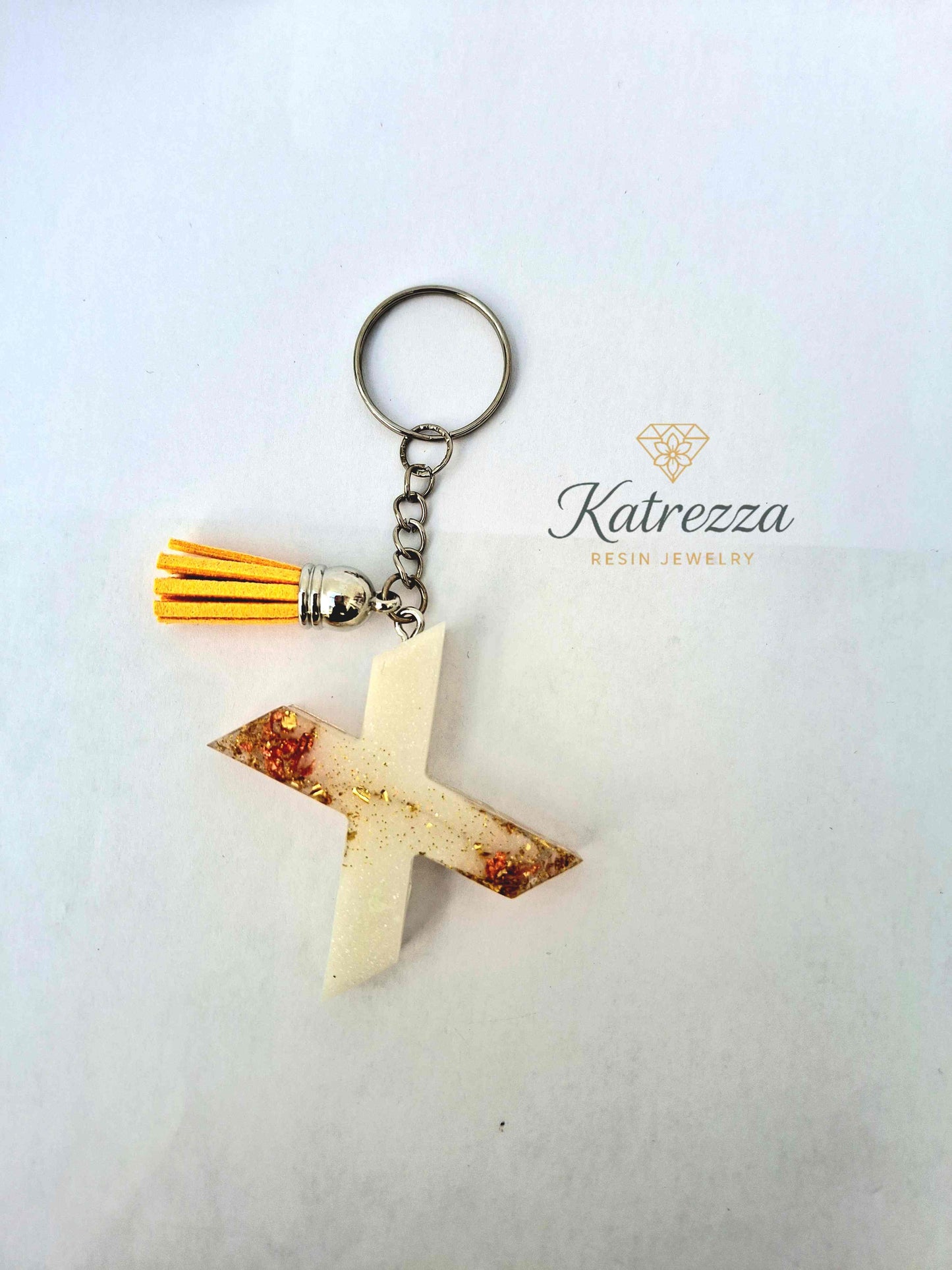 Close-up of resin letter X keychain with gold foil and glitter details.