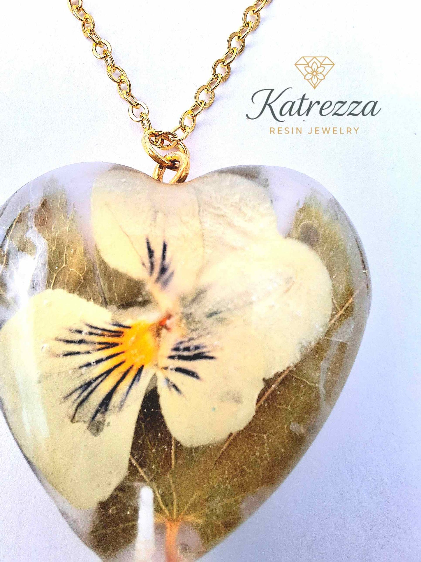 “Heart resin pendant with preserved real pansy flower inside, gold chain detail – Katrezza handmade jewelry.”
