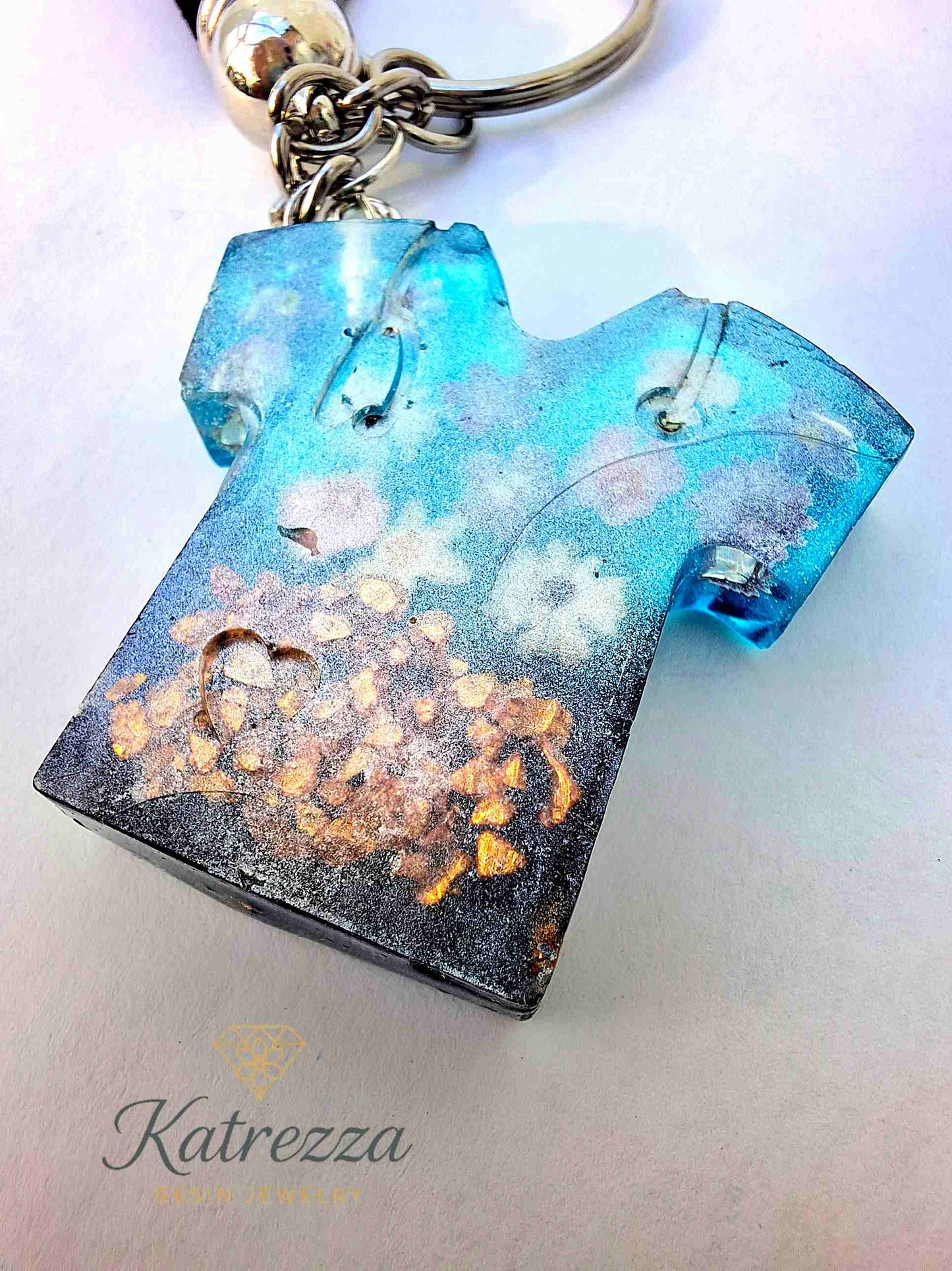Detailed view of resin T-shirt keychain with blue flower stickers inside.