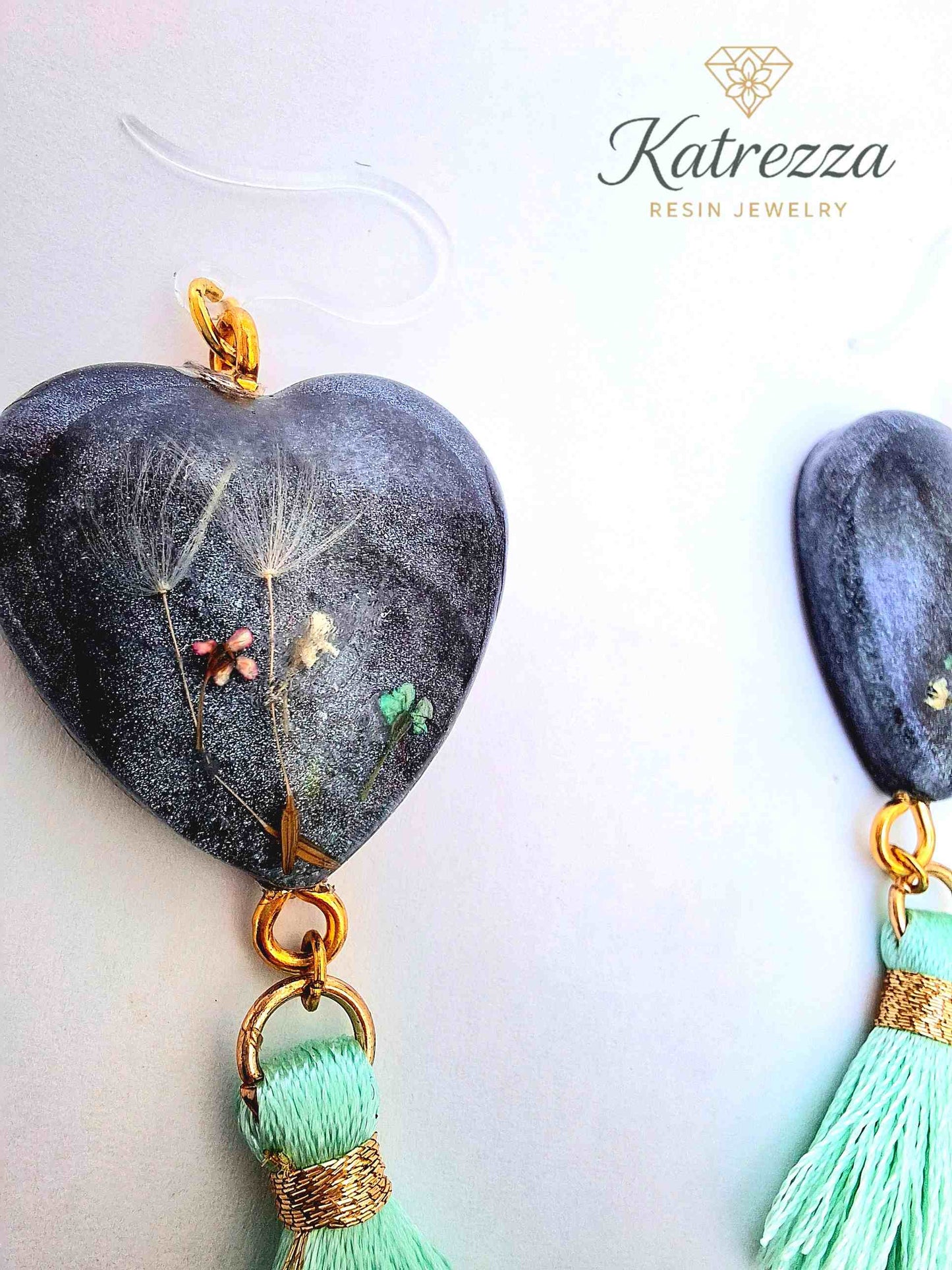 “Close-up of handmade resin earrings with dandelions and tiny flowers preserved inside.”