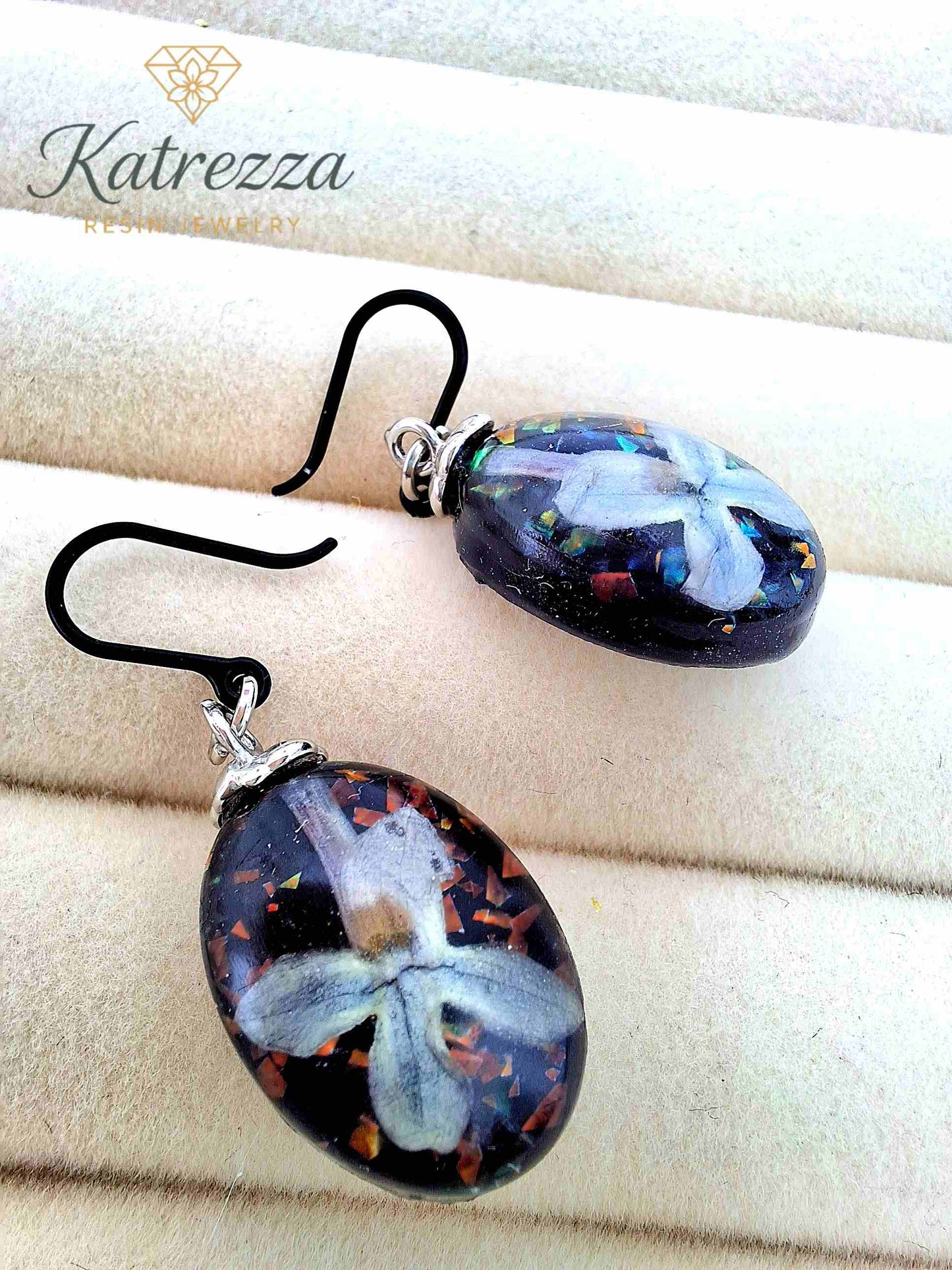 Close-up of oval resin earrings with lilac flower design