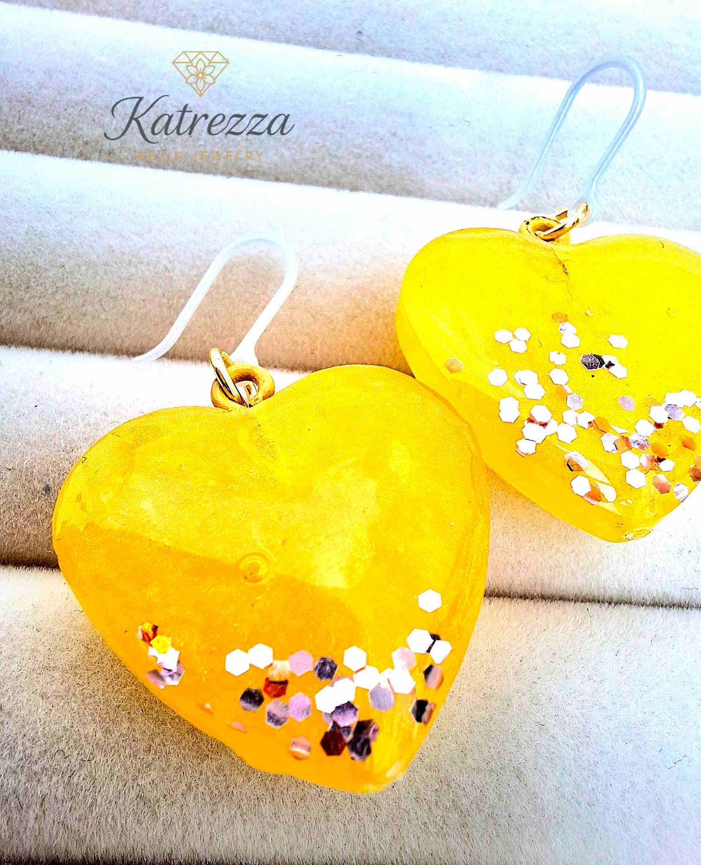 Yellow resin heart earrings with golden glitter accents