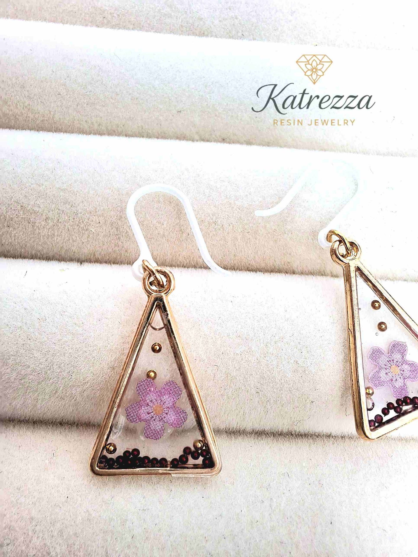Close-up of triangle resin earrings with pink flower accents – 2.5 cm