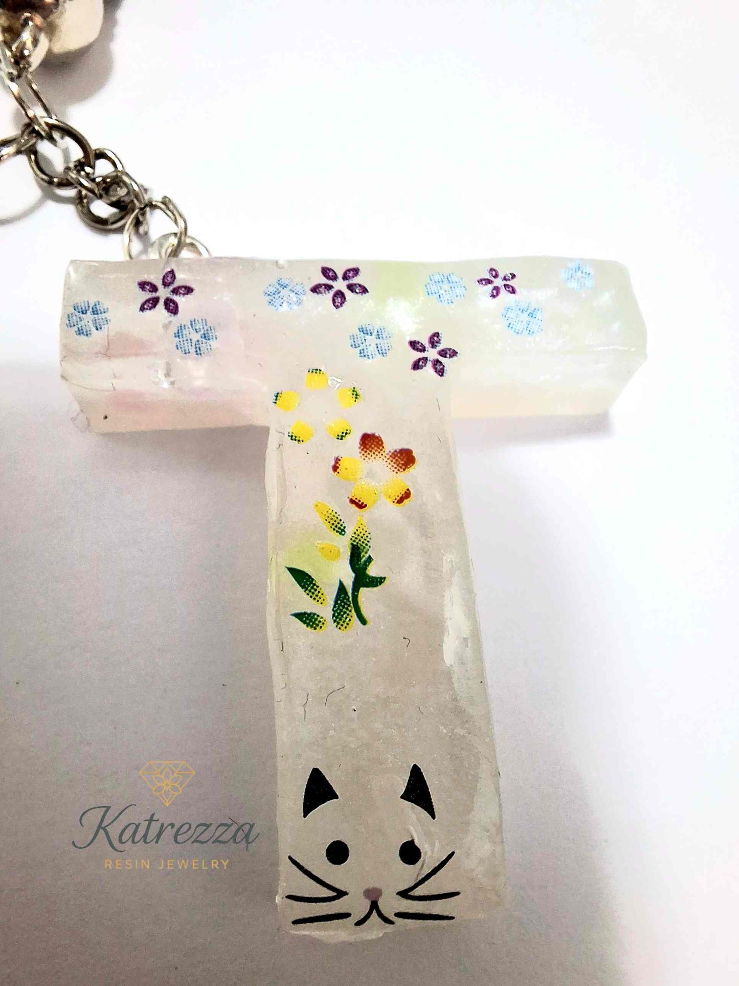 Close-up of resin T keychain showing flower stickers and cat face detail.