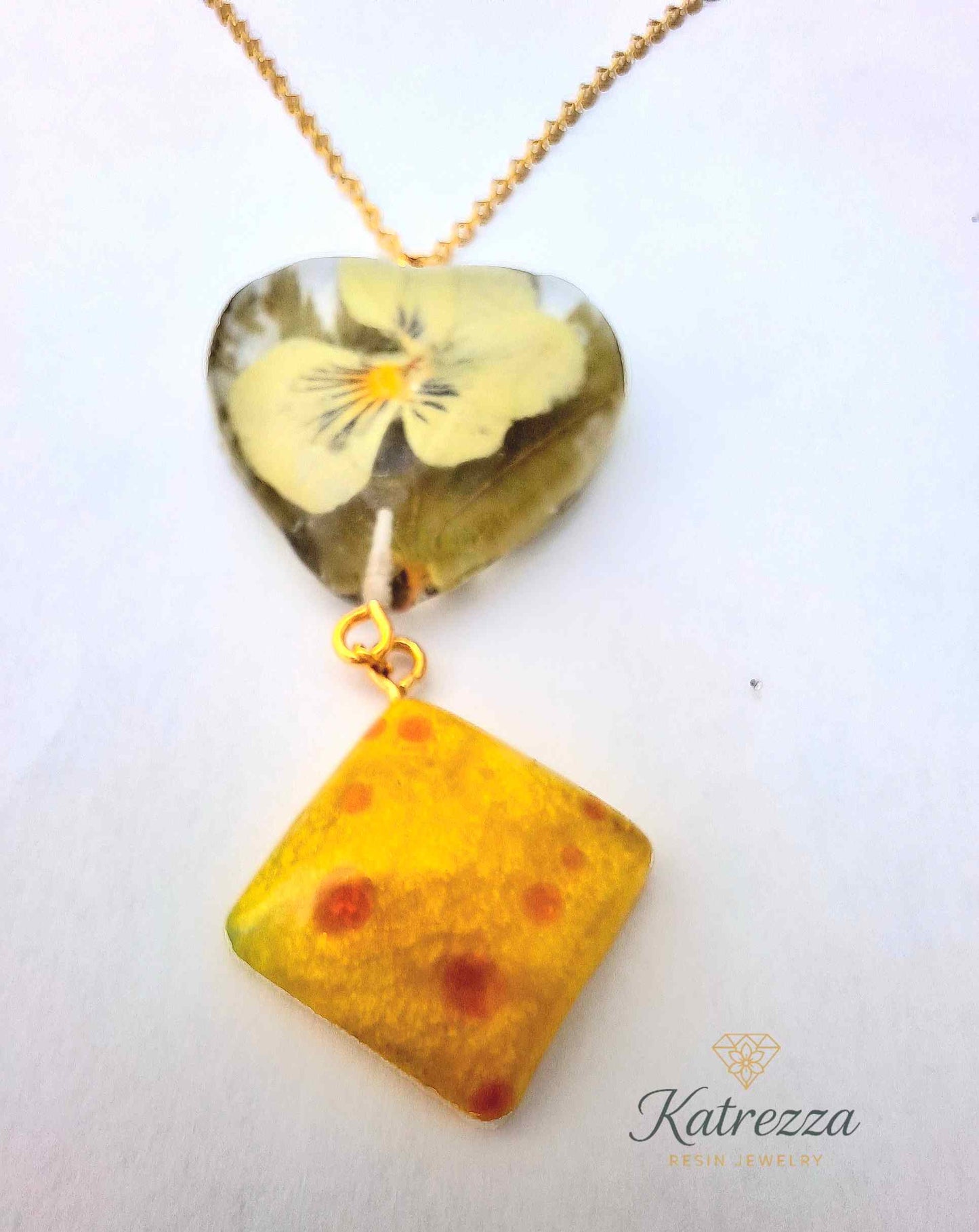 “Resin necklace with heart-shaped pansy flower pendant and yellow diamond resin charm on gold chain – Katrezza artisan jewelry.”