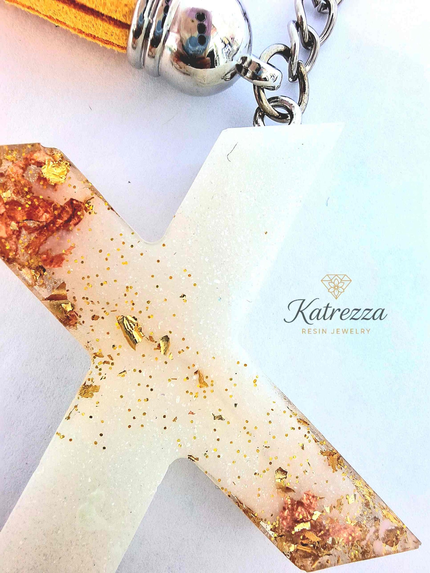 Resin letter X keychain with gold flakes attached to silver keyring.