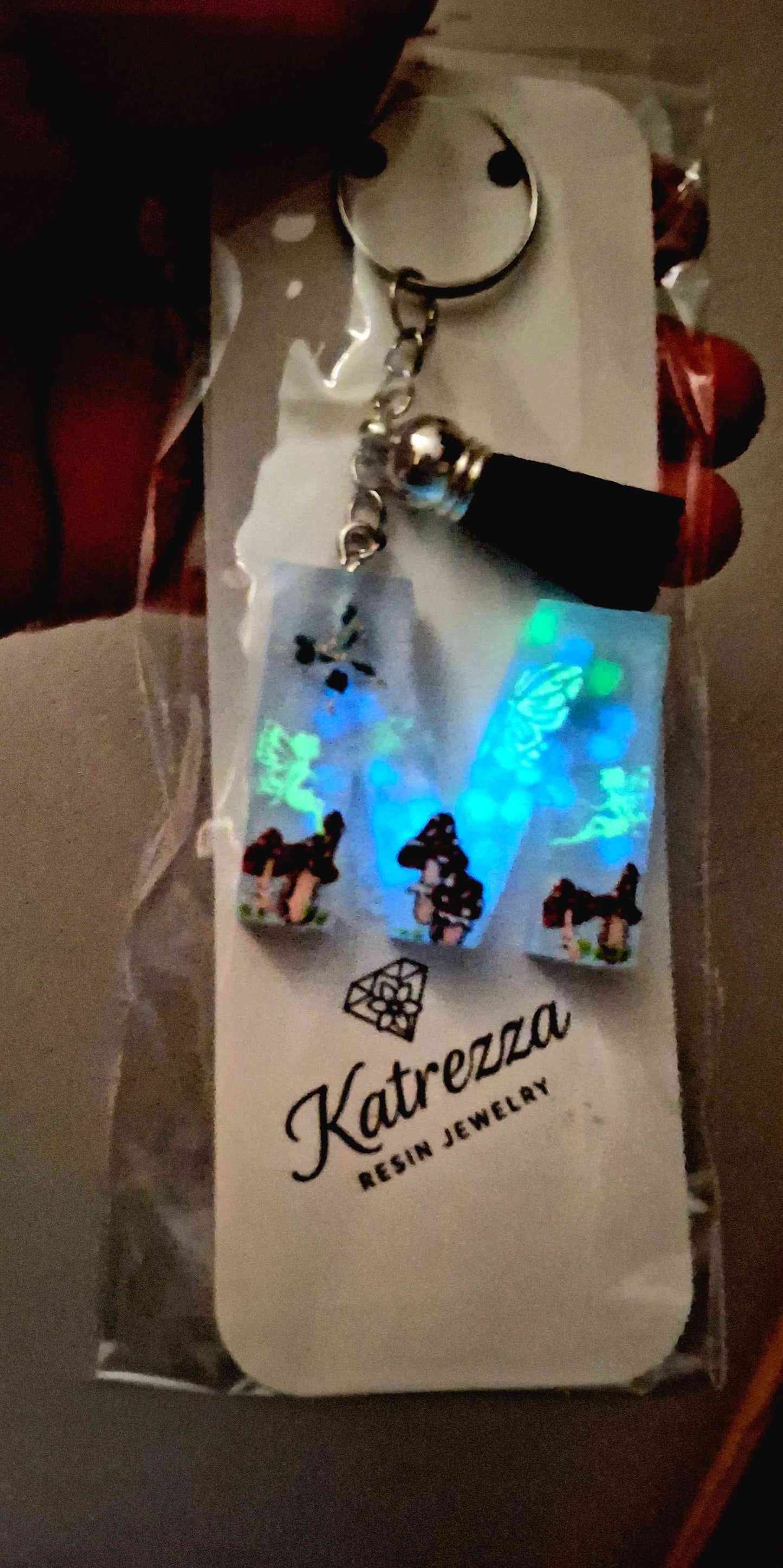Artistic resin M keychain with mushrooms, butterflies, and fantasy details.