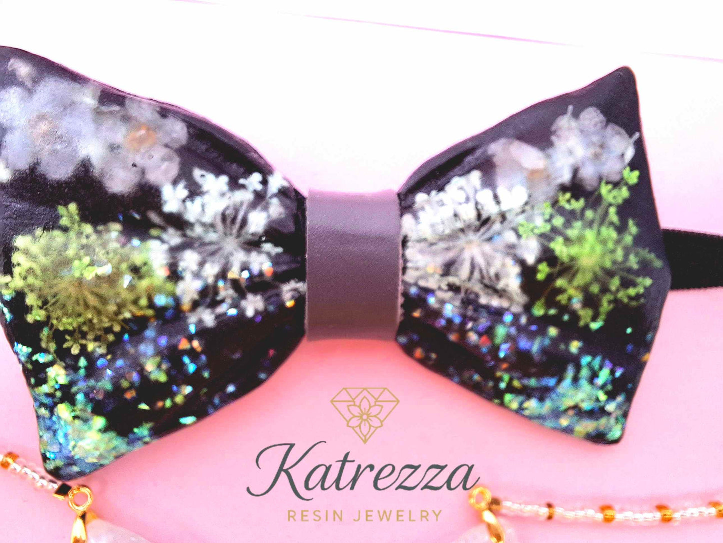 Close-up resin bow tie with green flowers glitter