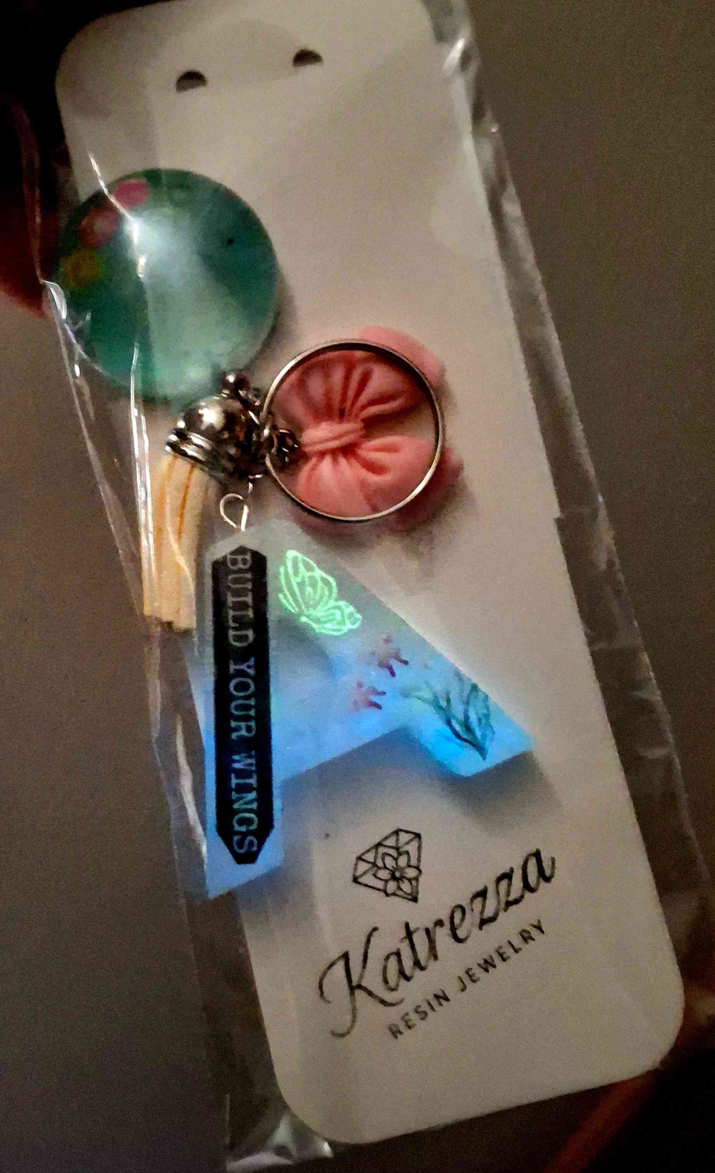 Glow-in-the-dark resin letter A keychain with quote and flower design.